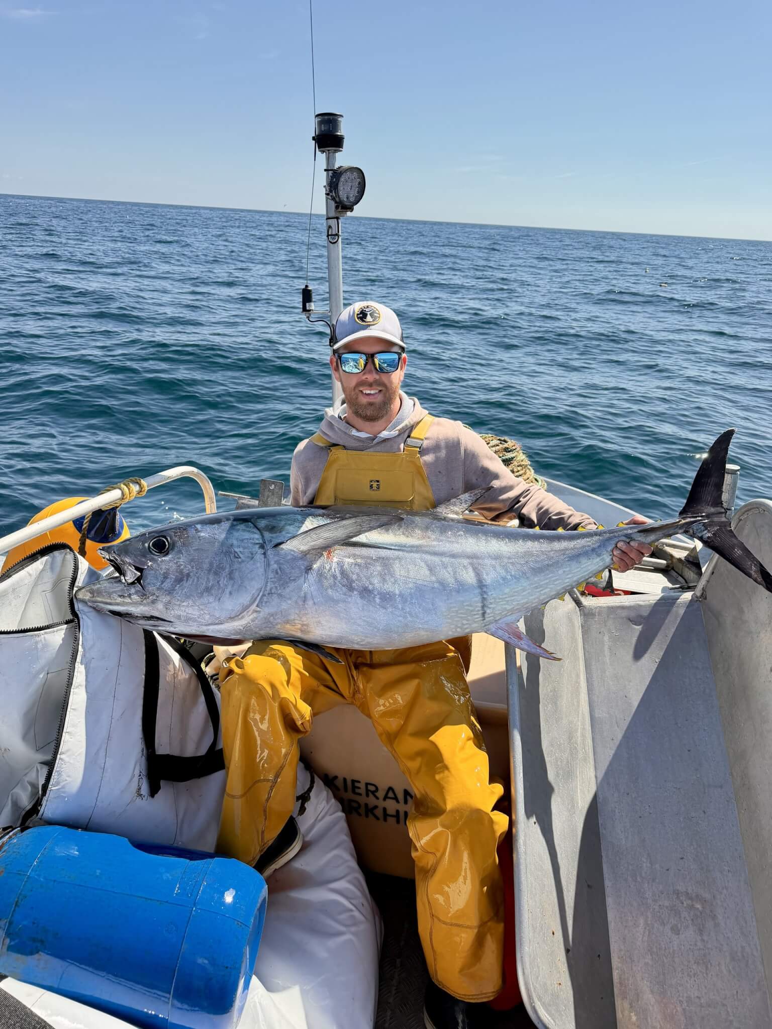 Fisherman holding a bluefin tuna aboard a small boat at sea