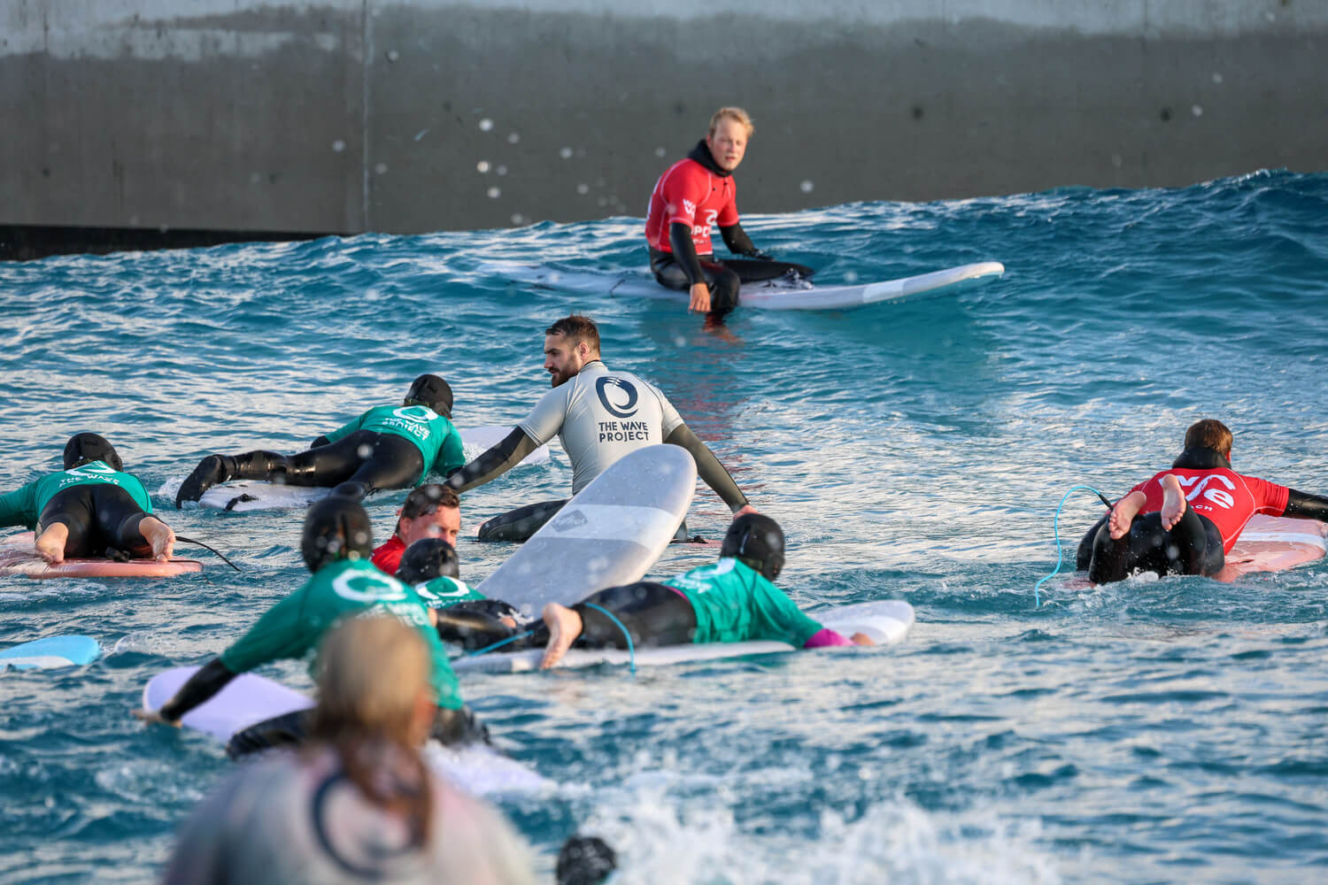 Young people paddling out with Wave Project mentors at an inland wave pool