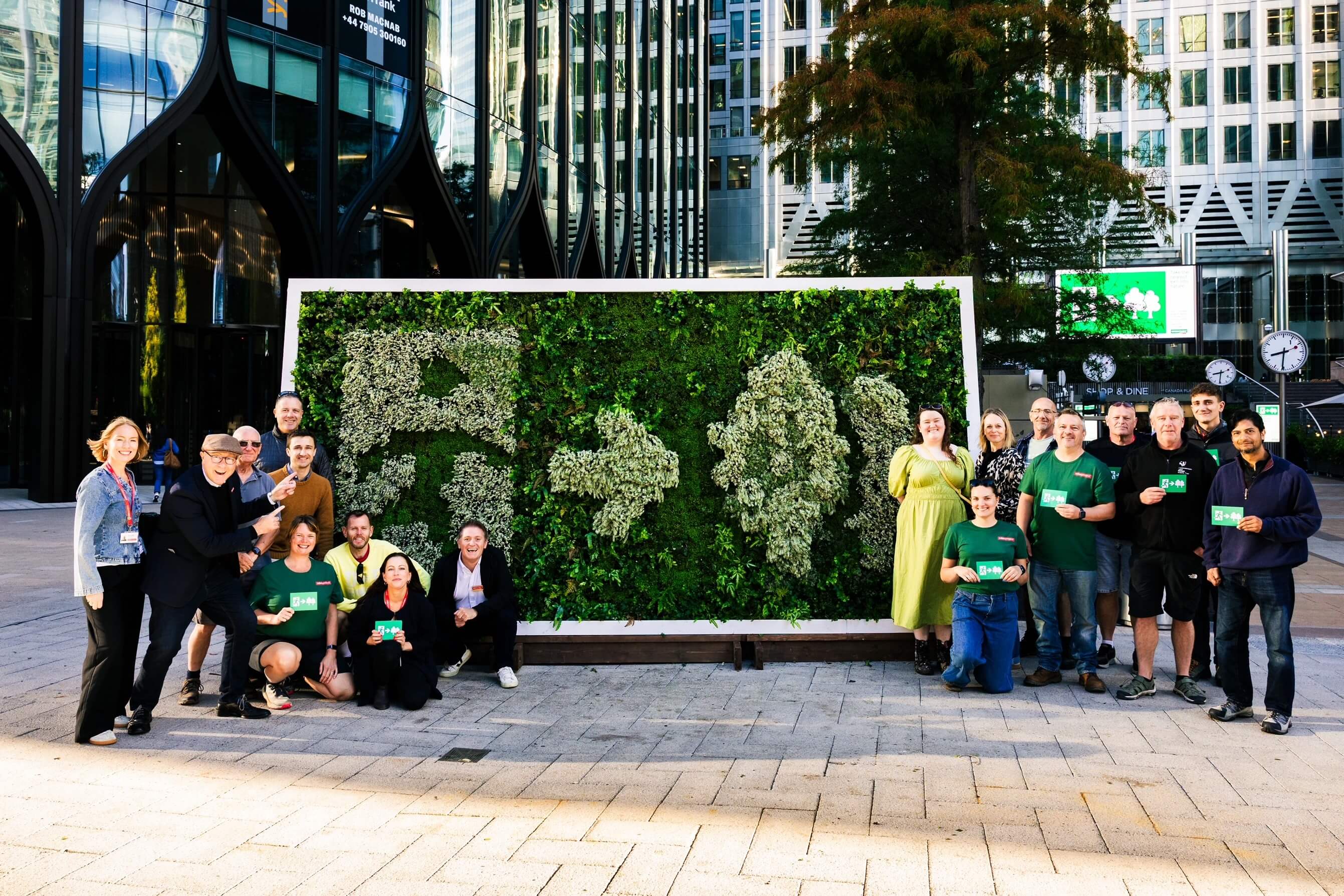 Volunteers and staff pose beside the living Emergency Exit sign at Canary Wharf