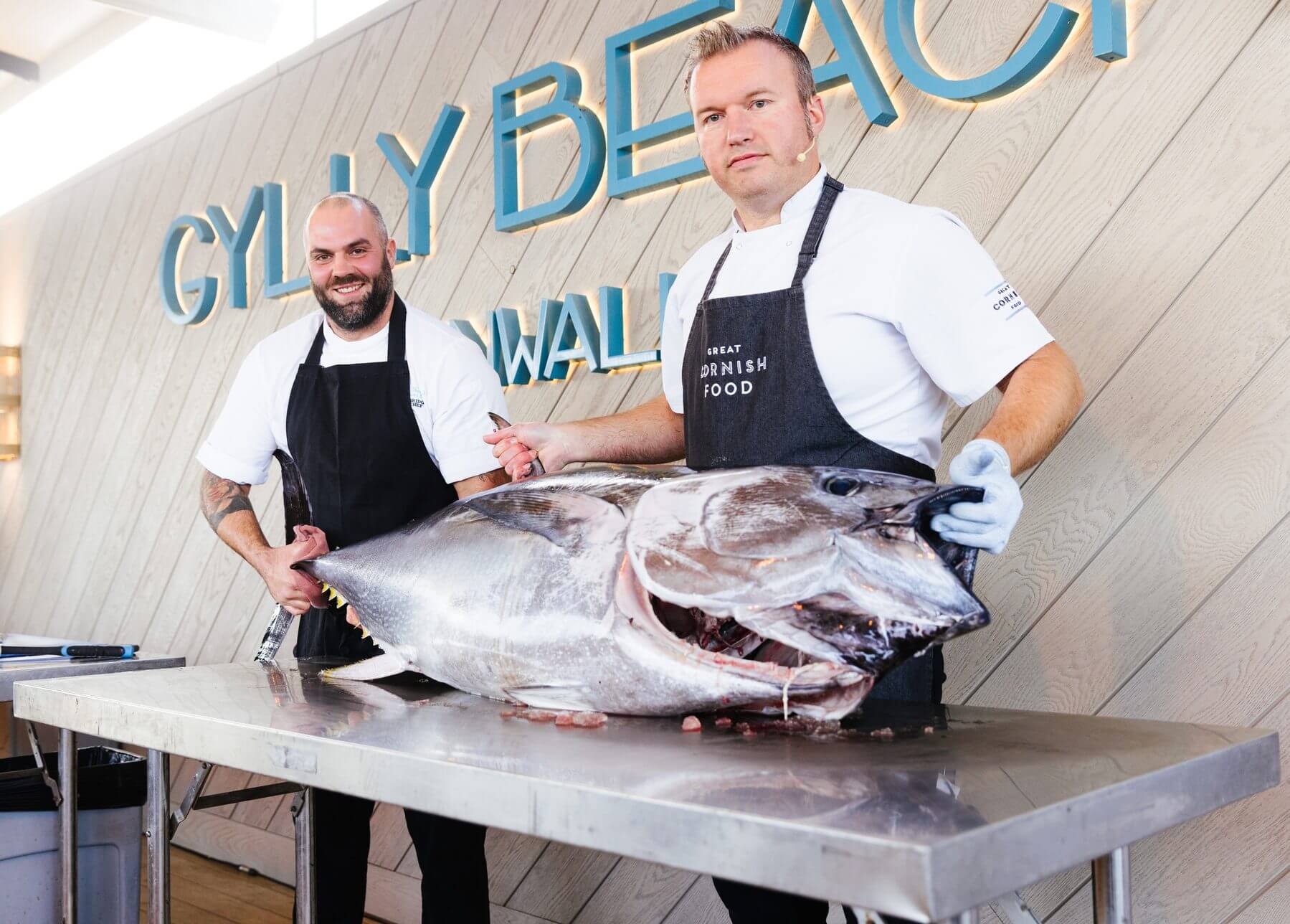 Two chefs with a whole Cornish tuna at Gylly Beach in Falmouth