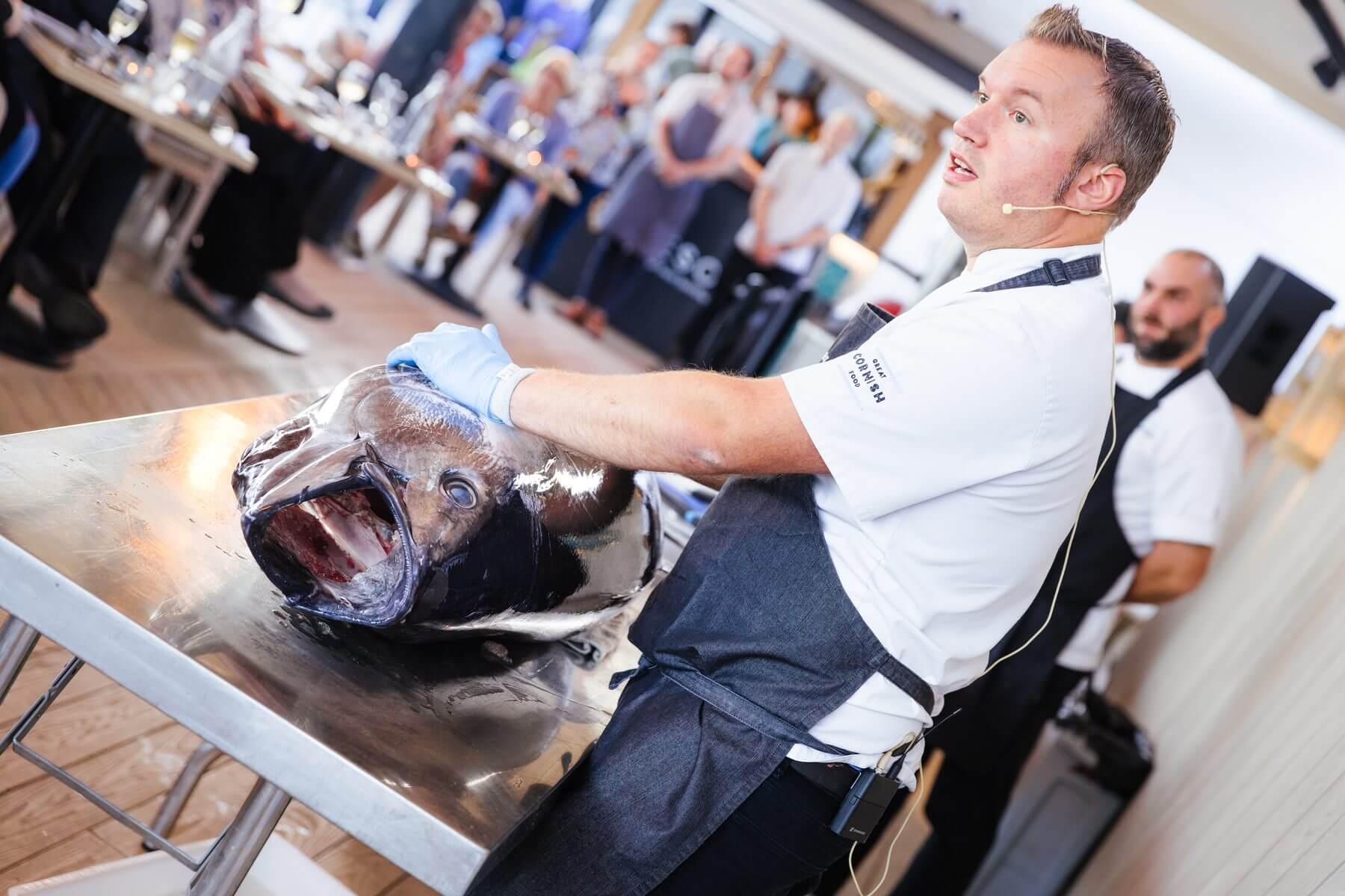 A chef holding the head of a freshly prepared tuna