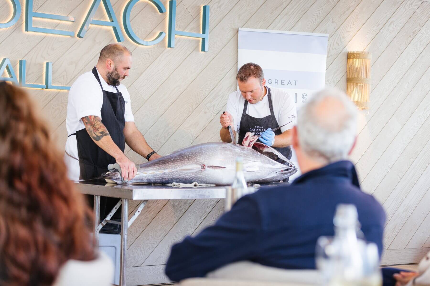 Chefs preparing a whole tuna in front of guests at Gylly Beach