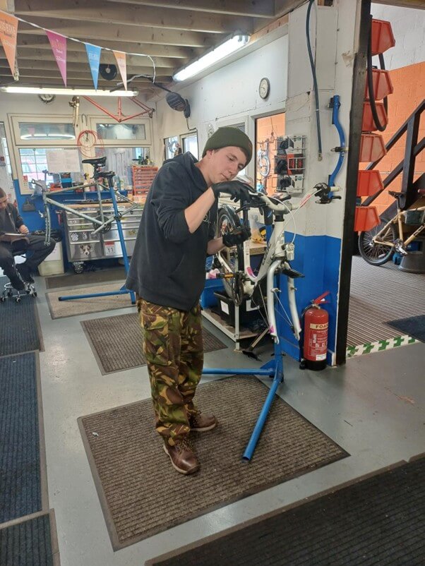 Harry working on a bike in a workshop as part of the YEP trial