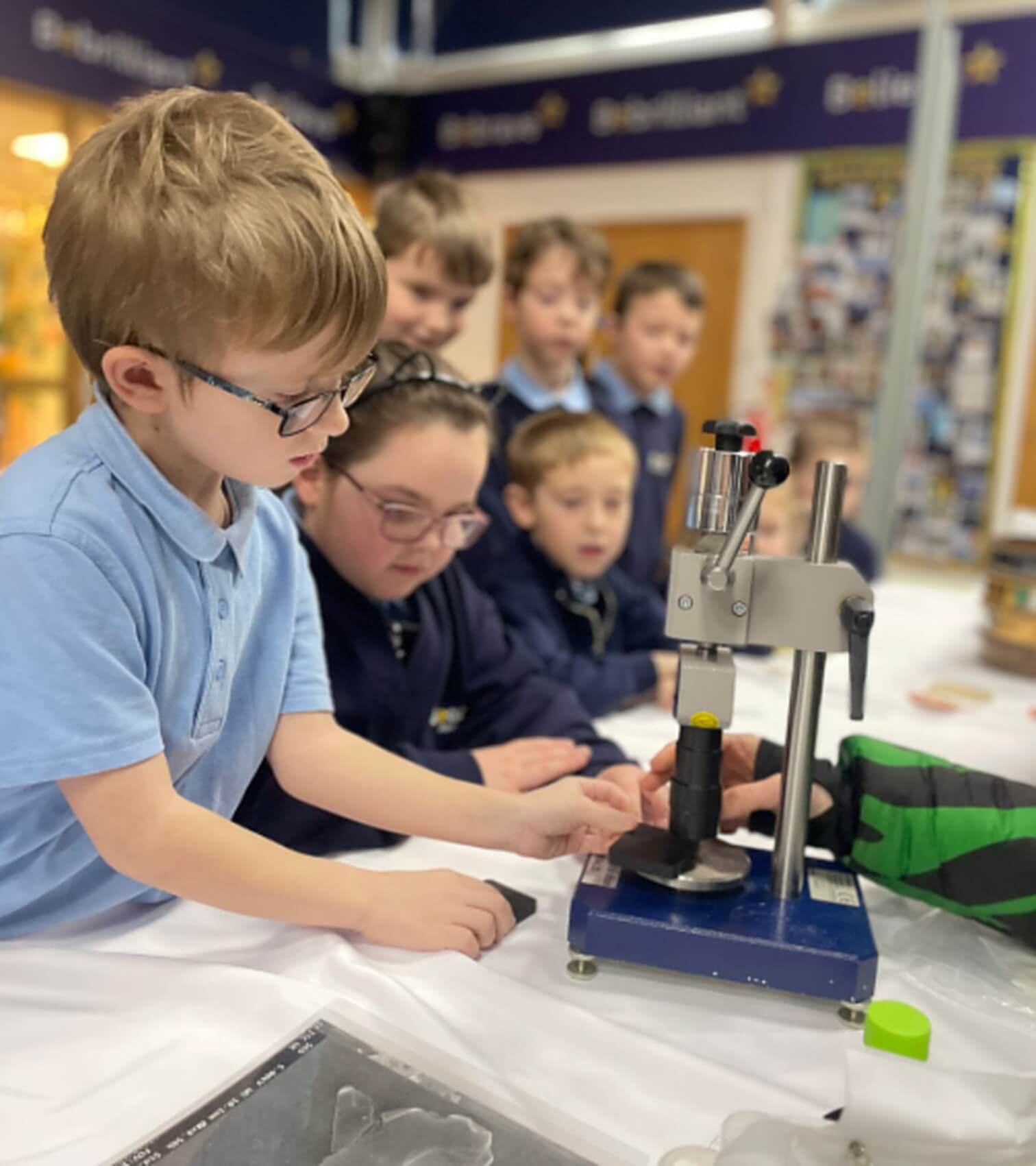 Schoolchildren examining a sample under a microscope at an Imerys education event