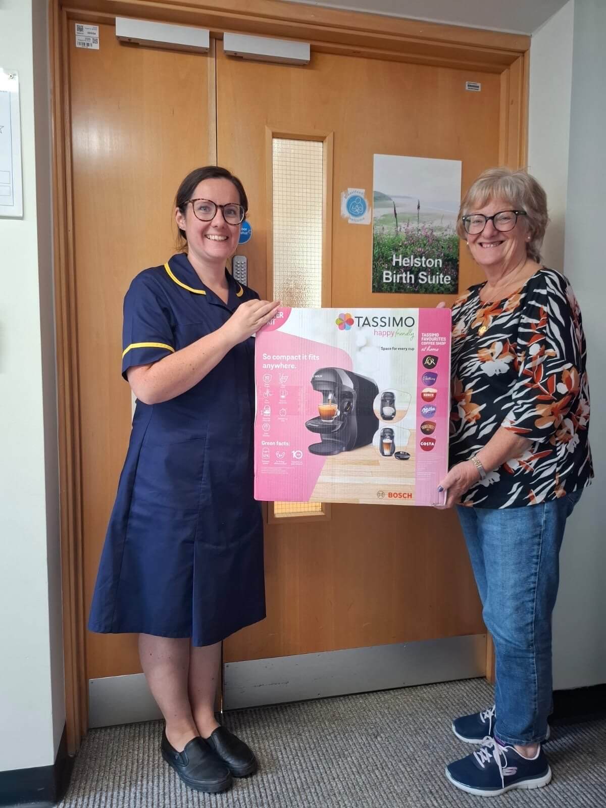 Janice and Fiona holding a boxed coffee machine outside Helston Birth Suite