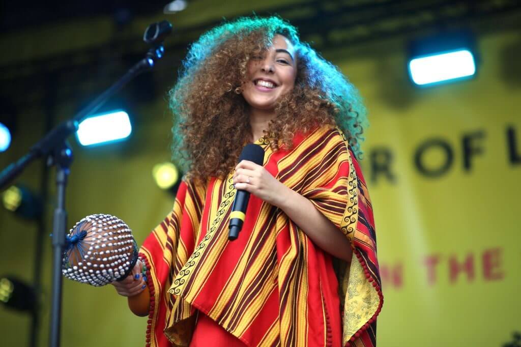 Kenza Blanca performing on stage with a microphone