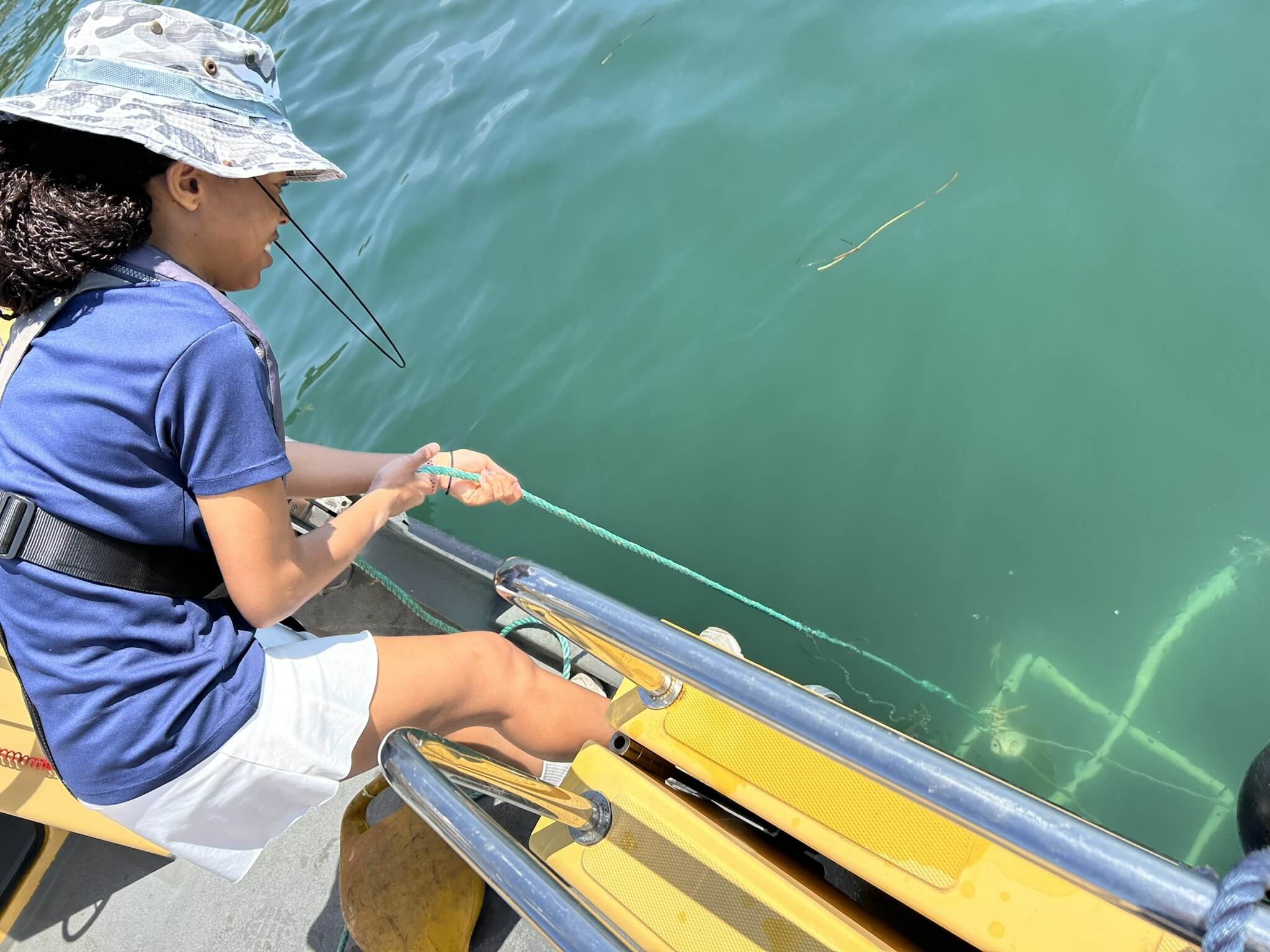 Khianna Lee lowering an underwater camera rig from a boat in Falmouth Harbour