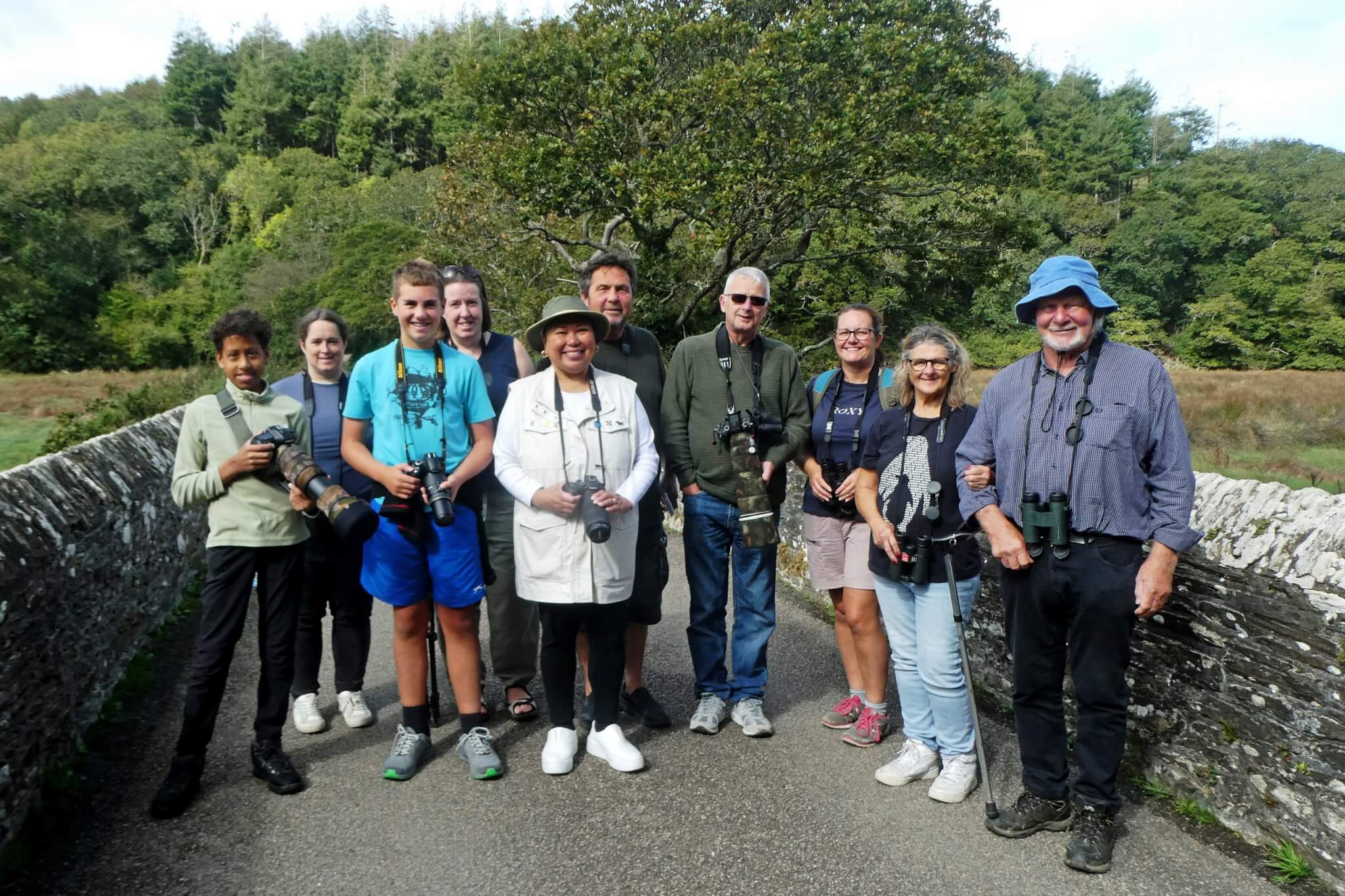 Birdwatching group with cameras and binoculars on a stone bridge at Ruan Lanihorne