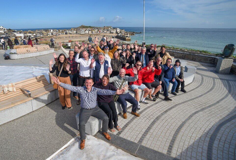 Project partners wave from the new granite seating on the Malakoff in St Ives with the harbour behind