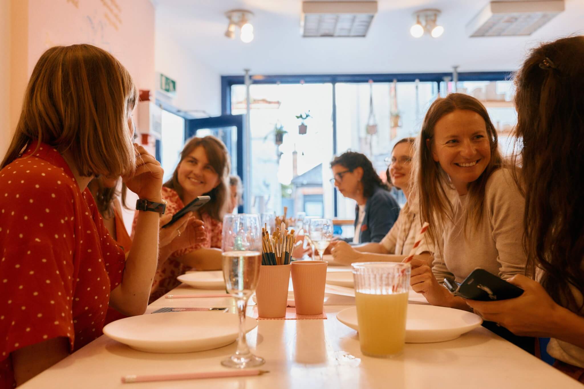 Friends chatting around a table at a pottery painting evening at Starglazers in Falmouth