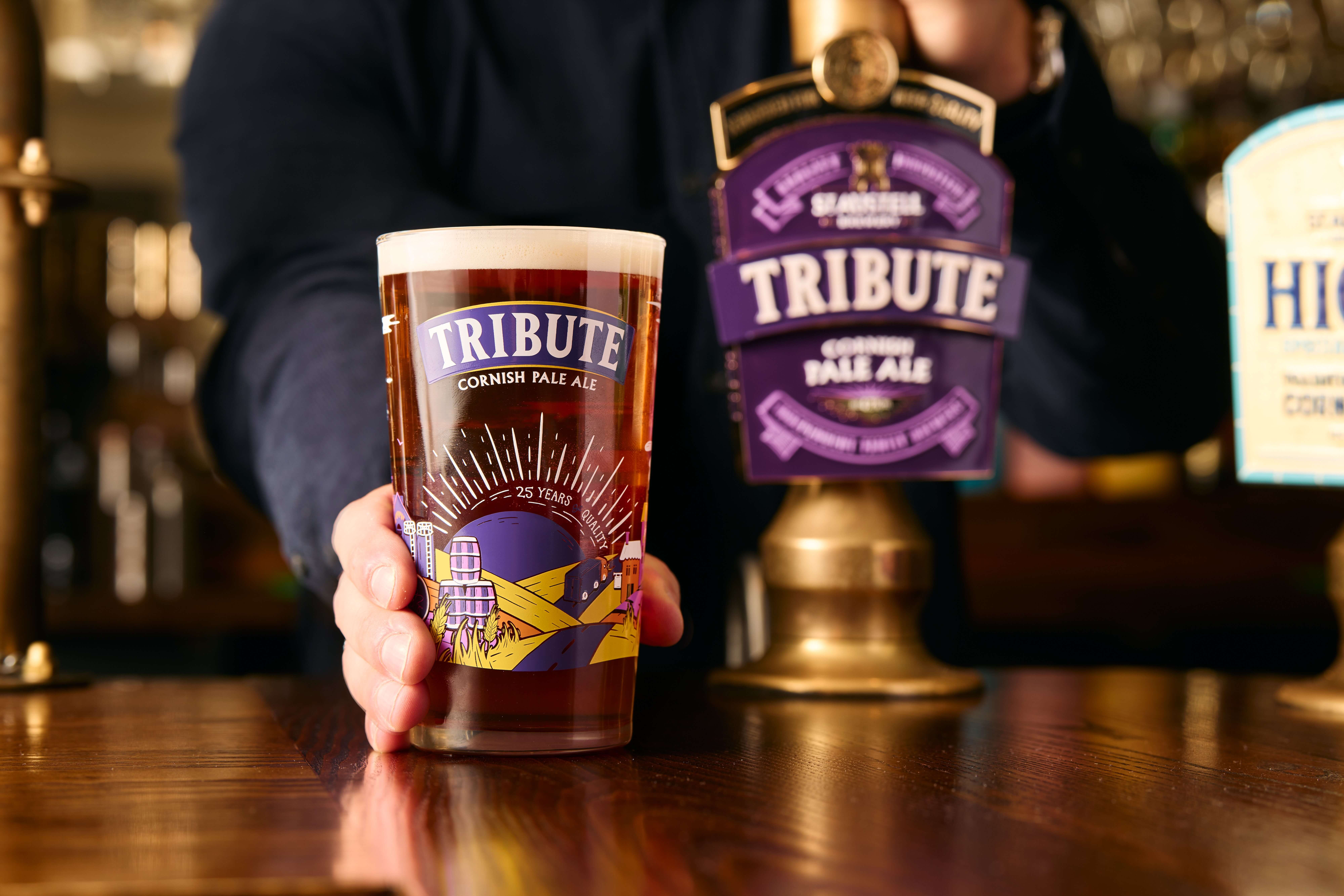 A pint of Tribute Cornish Pale Ale on a pub bar next to the Tribute pump clip