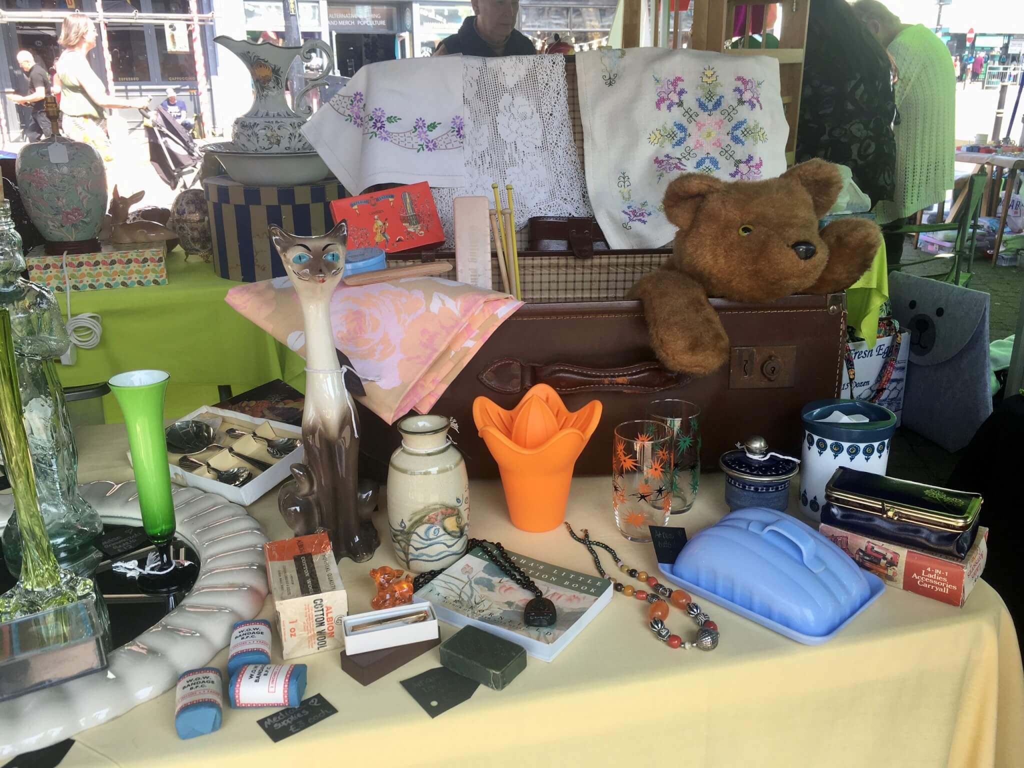 Embroidered linens, a teddy bear and retro homeware on an antiques stall in Truro