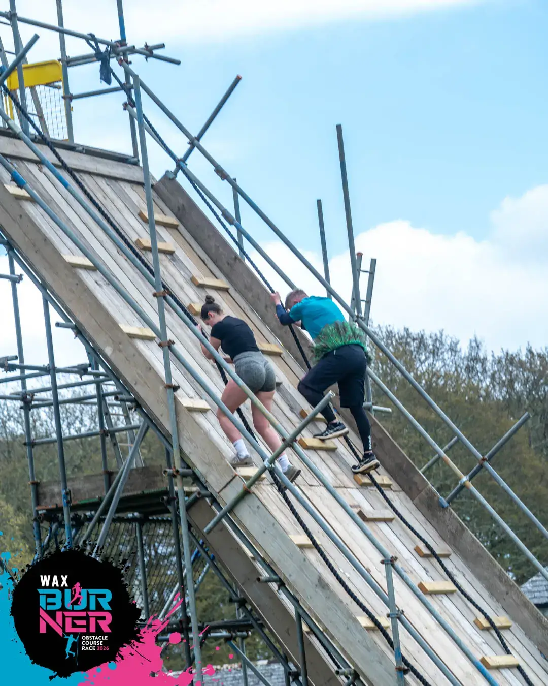 Participants climbing a wooden ramp obstacle at WAX Burner