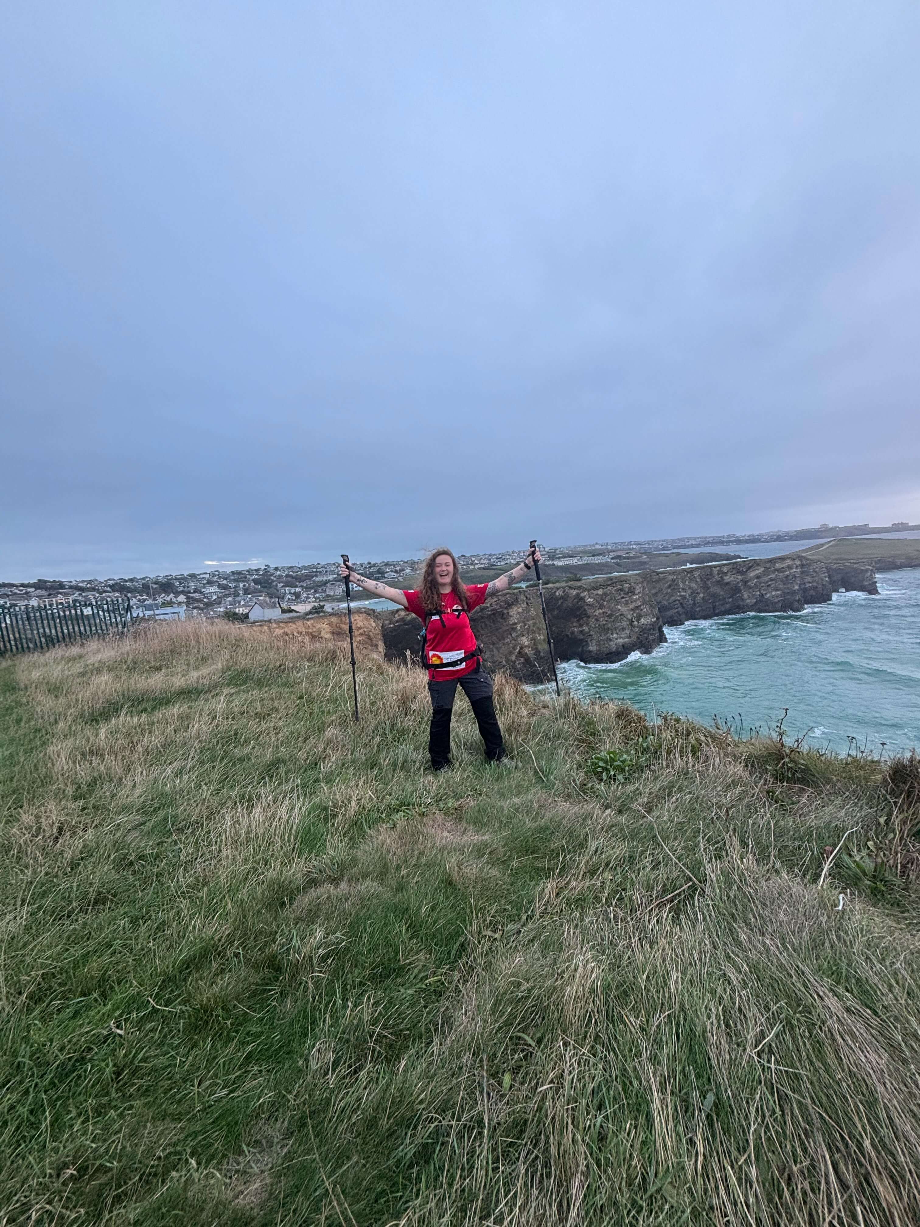 Skye Owen with arms raised on the cliff path during her 24-hour walk