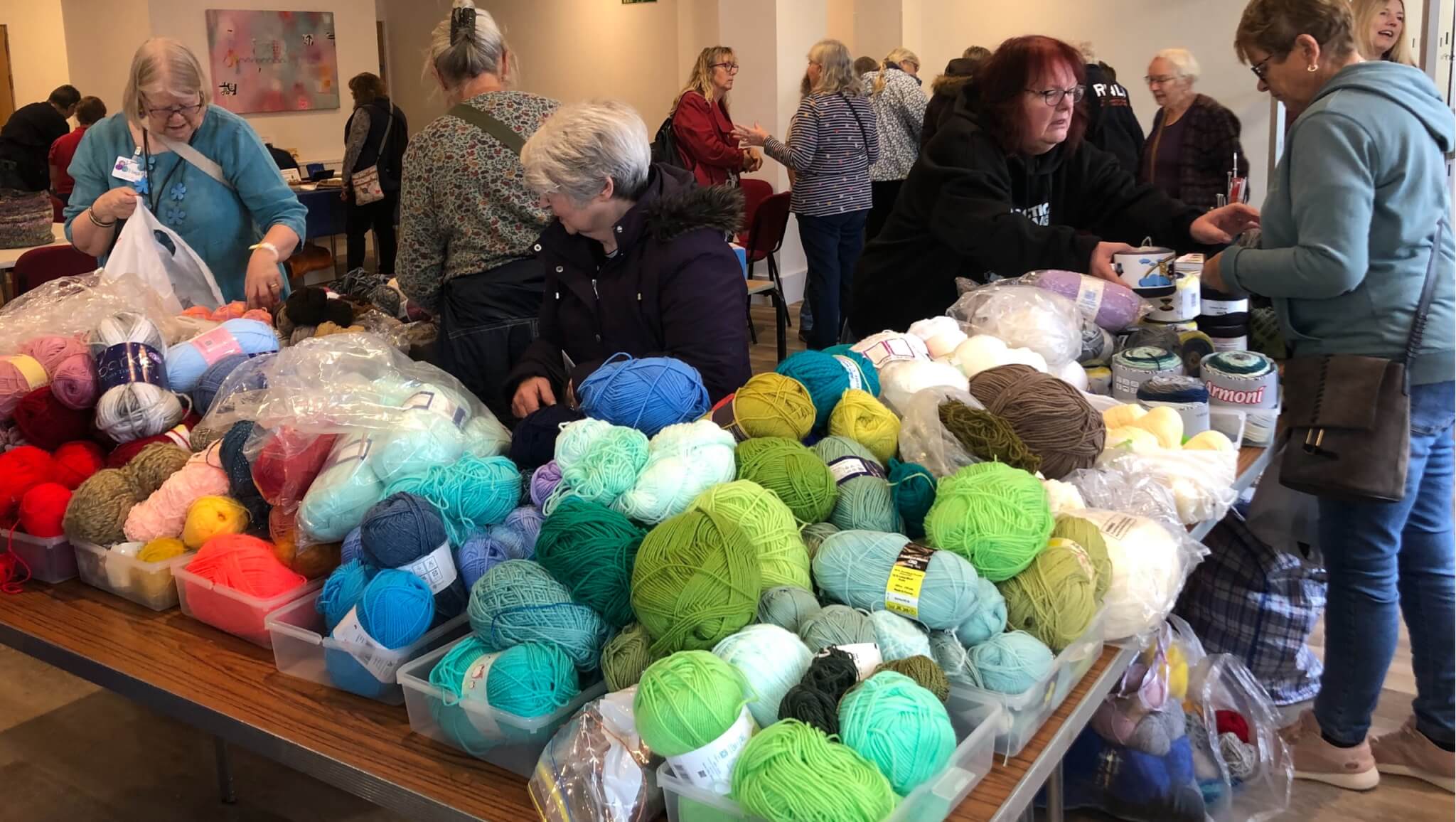 Shoppers browsing tables piled with yarn at the Liskeard Yarn Swap