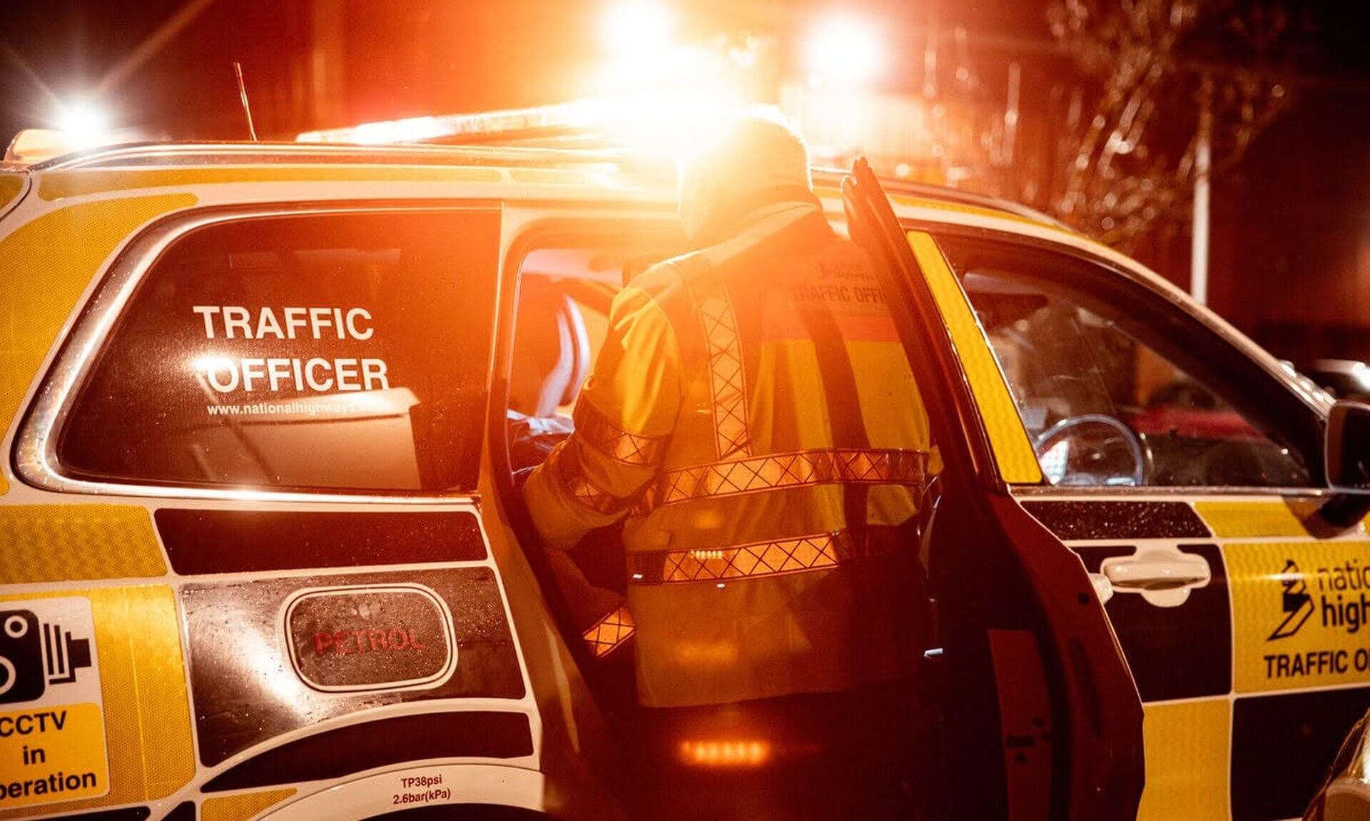 National Highways traffic officer at a patrol vehicle at night