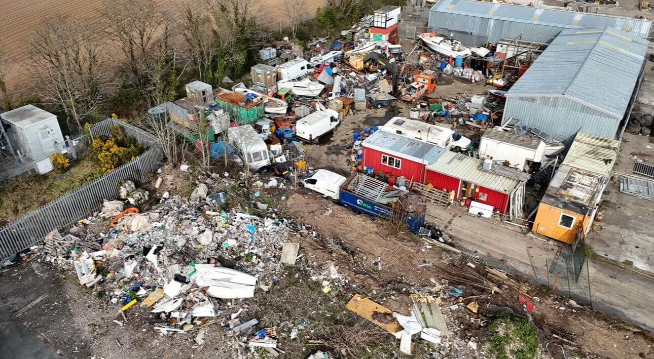 Aerial view of the site before clearance, showing fly-tipped waste and vehicles