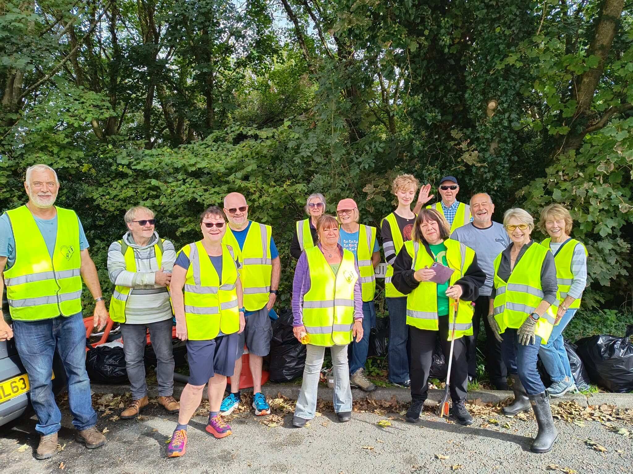 Bodmin Tidy it Team volunteers in hi-vis vests beside bags of collected rubbish