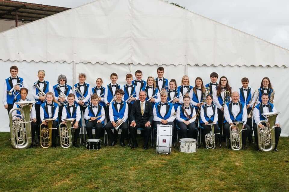 Camborne Brass band members posing together in their blue and black uniforms