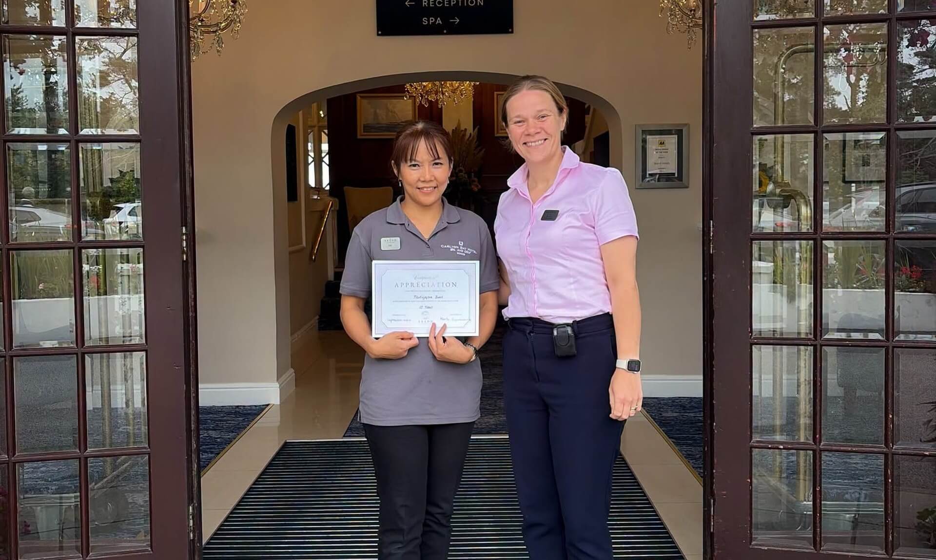 Tia and a colleague at the Carlyon Bay Hotel entrance with a ten years certificate of appreciation