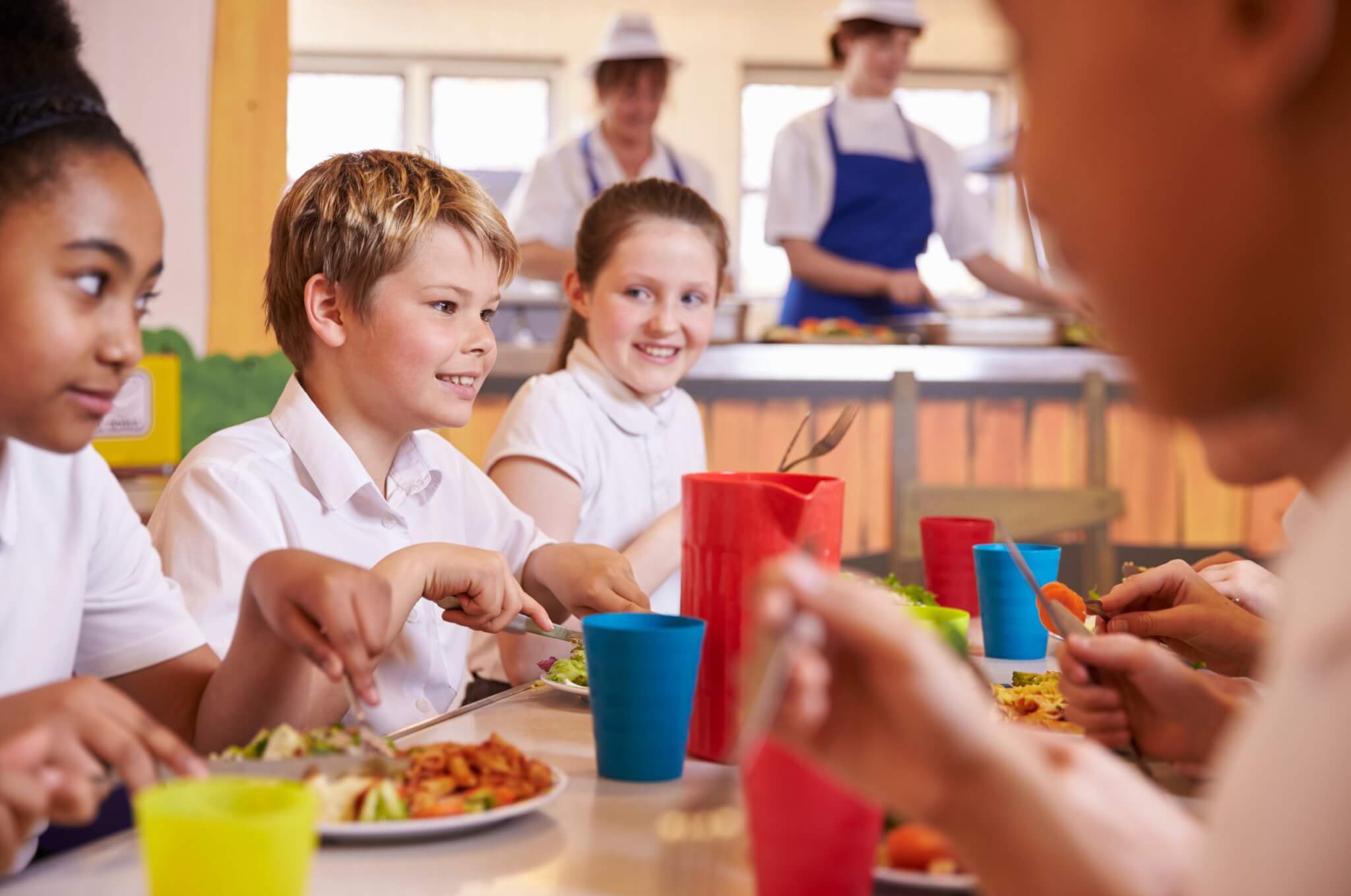 Primary school children eating lunch together in a school canteen
