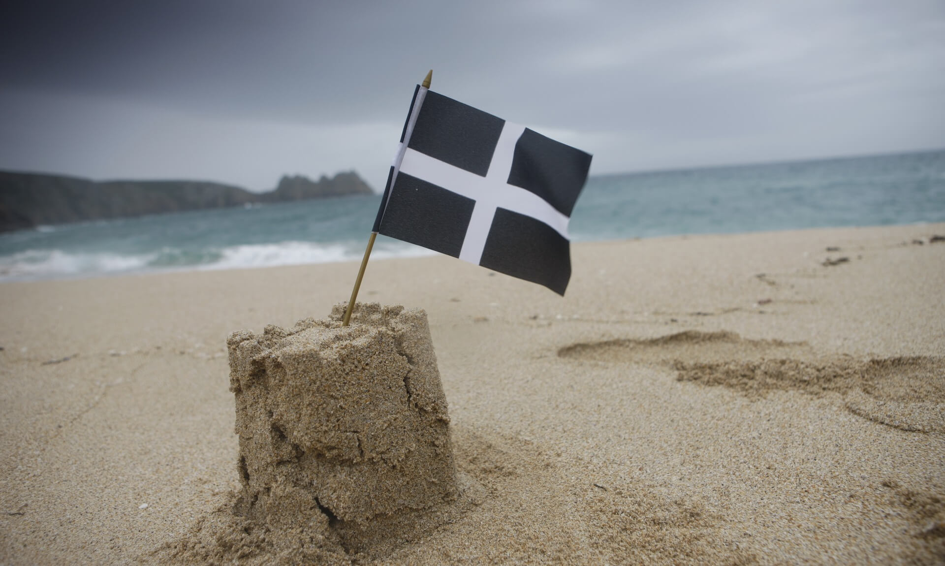 A St Piran's flag in a sandcastle on a Cornish beach