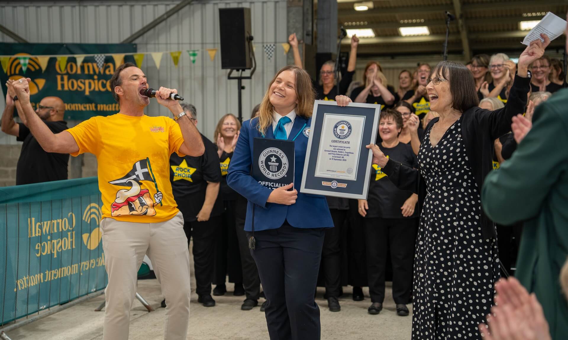 Johnny Cowling and a Guinness World Records adjudicator celebrate Cornwall Hospice's record cream tea party