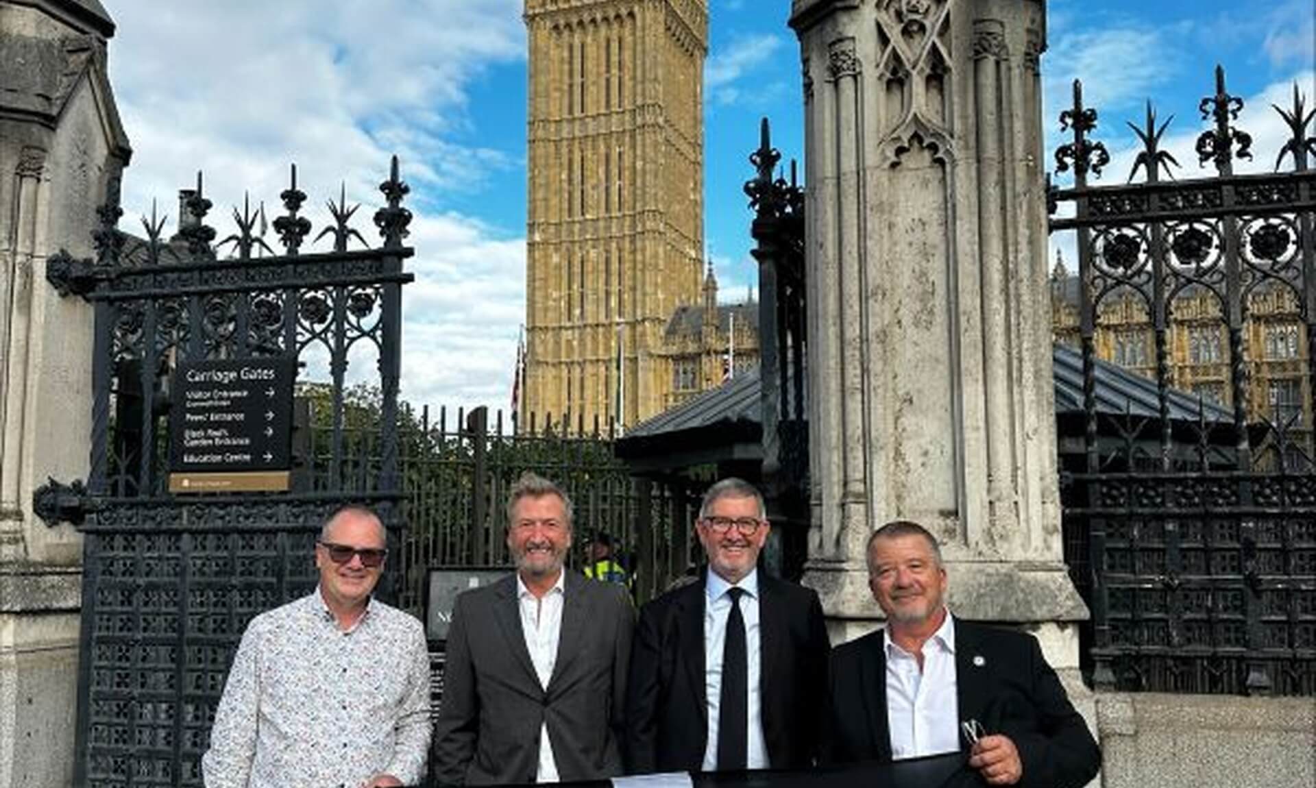 Cornwall representatives holding the Cornish flag outside the Houses of Parliament