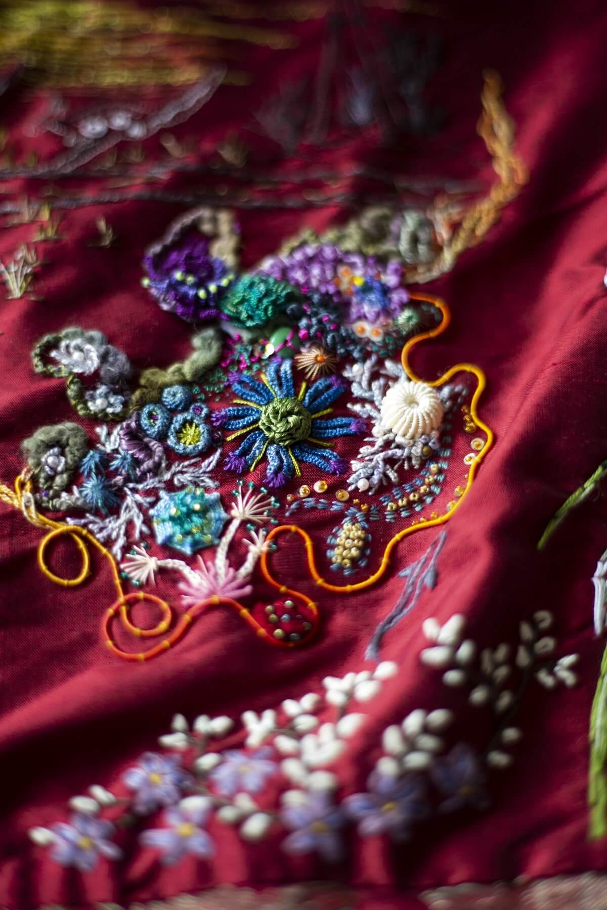Close-up of colourful embroidery on burgundy silk