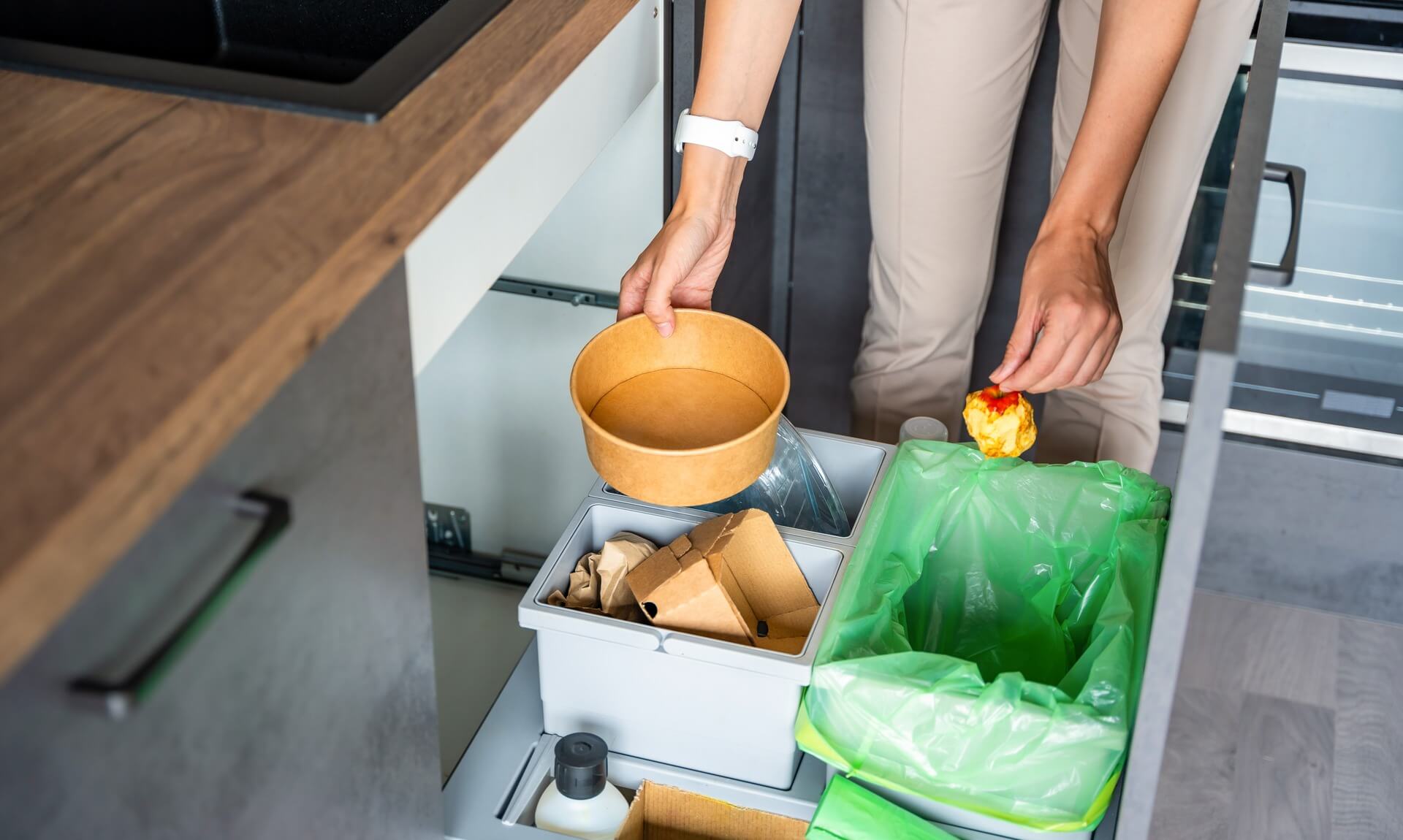 Person putting food waste and recycling into kitchen bins