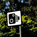 Speed camera warning sign in front of trees