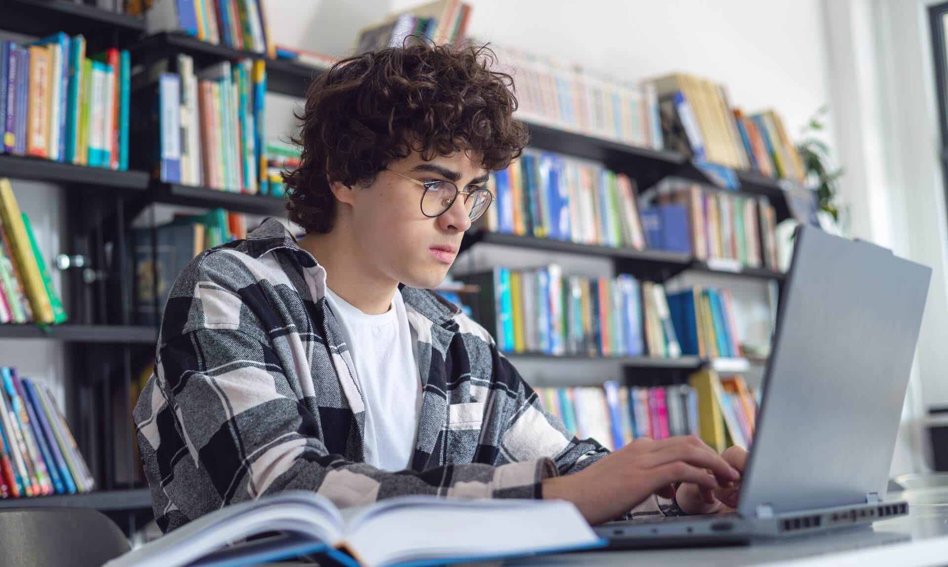 Teenage student working on a laptop in a library