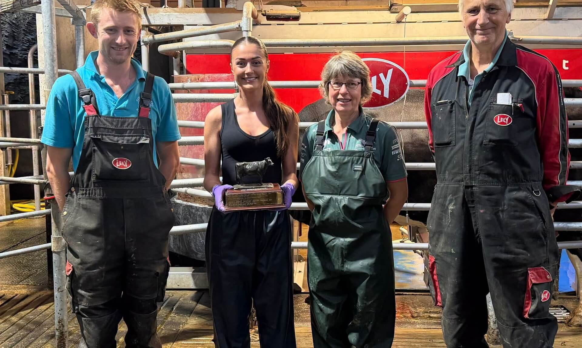 Holly holds her West Country Dairy Award trophy alongside three colleagues at a dairy unit