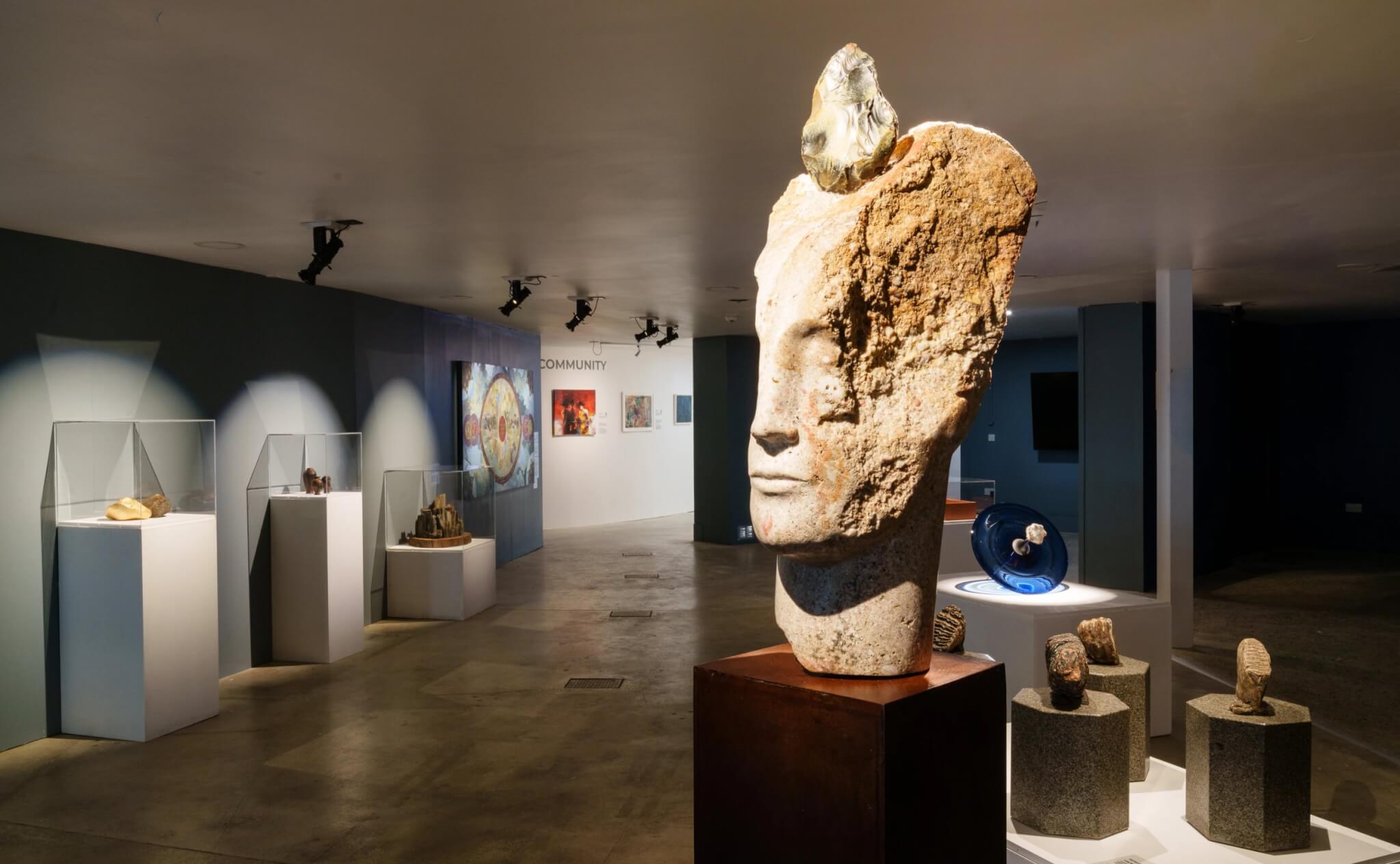 Emily Young's carved stone head sculpture with a prehistoric hand axe set into it, part of Extinction: Renewal at Eden Project