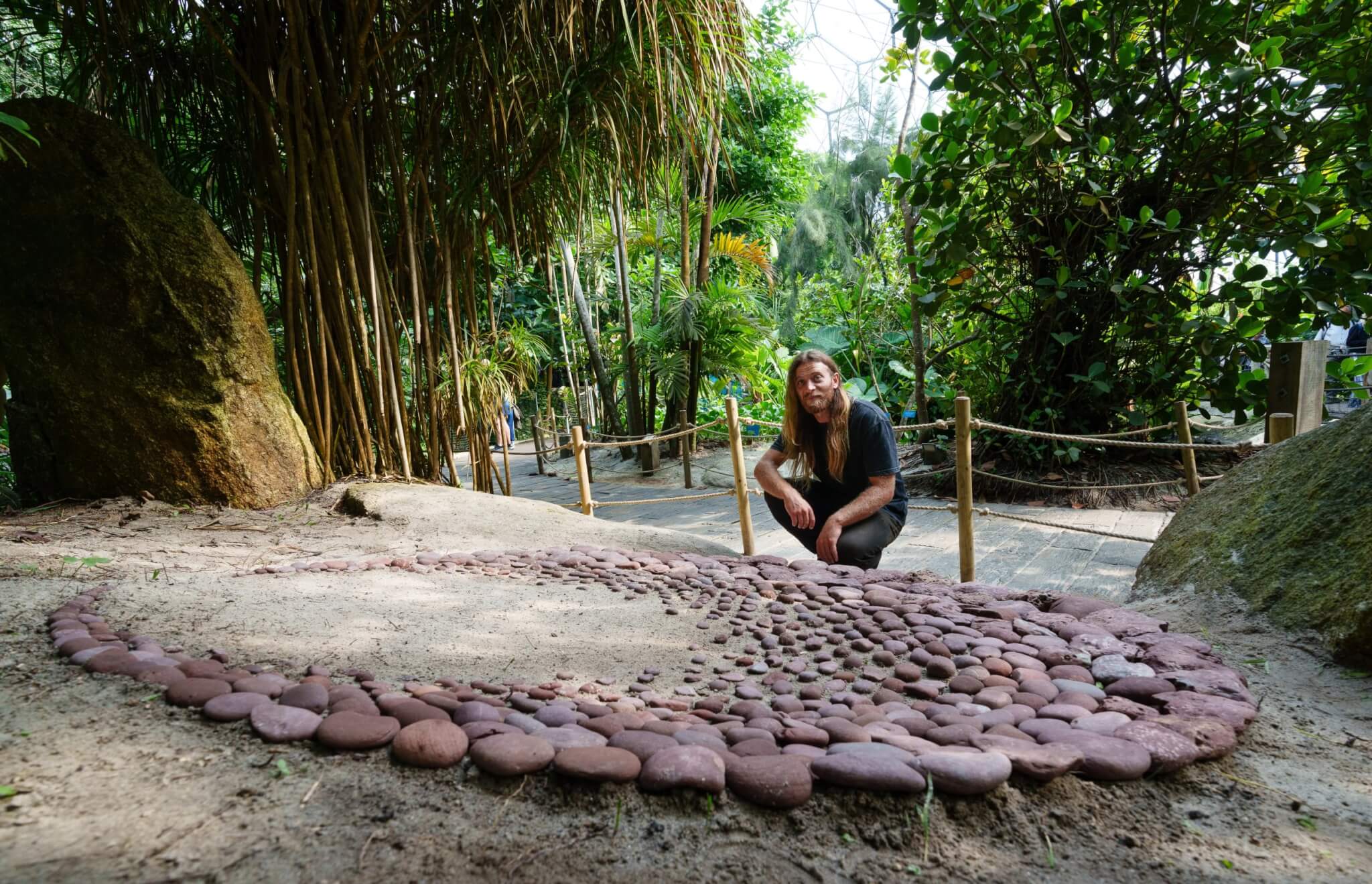 Jon Foreman's Stone Moon sculpture made from red sandstone, installed in the Rainforest Biome at Eden Project