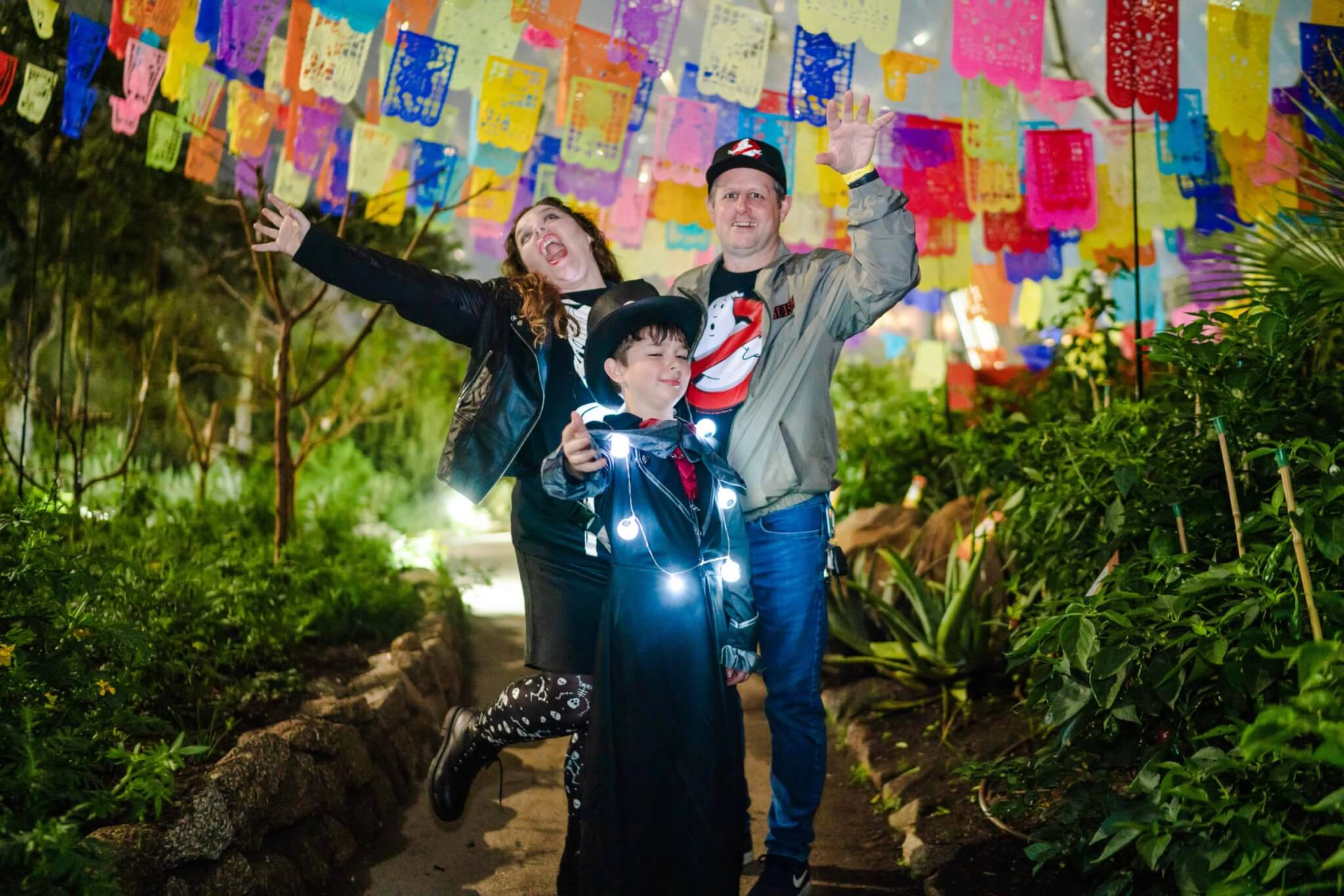 Family in Halloween costumes celebrating under colourful bunting at Eden Project Halloweden