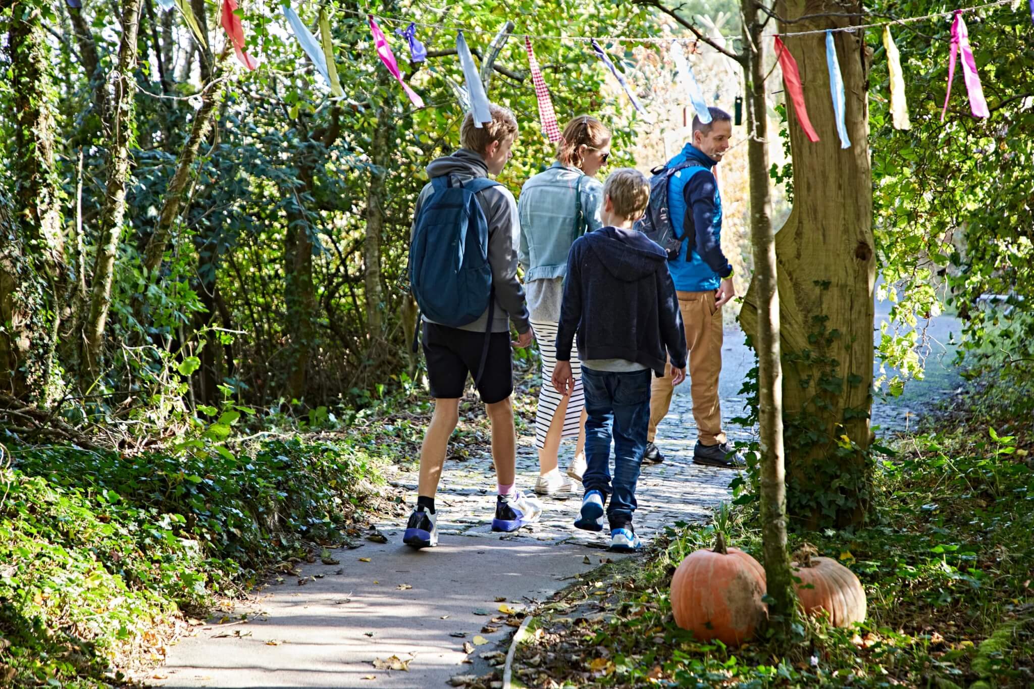 Family walking the woodland trail past pumpkins at Eden Project