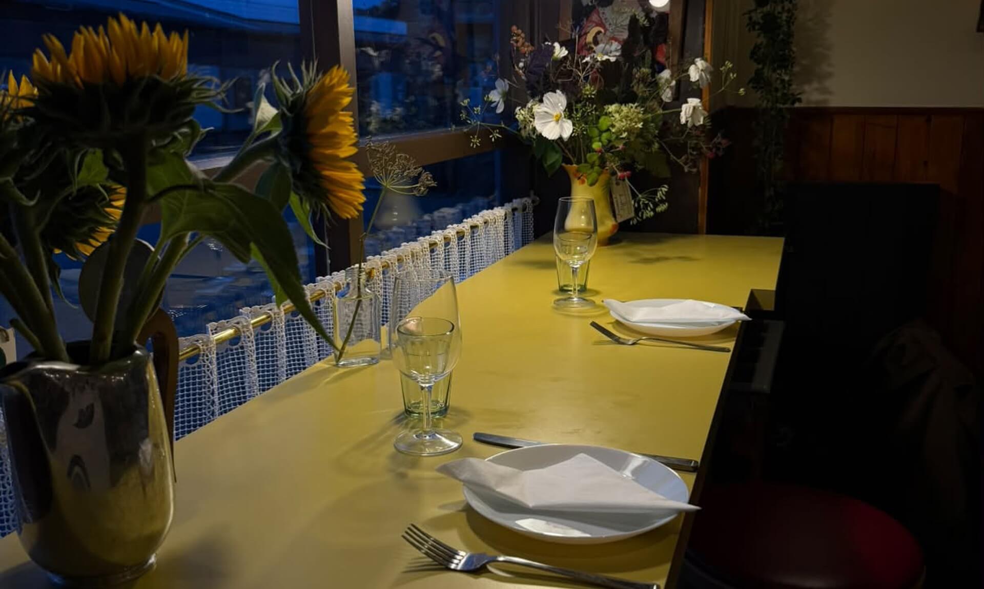 A table set for dinner at Favorita in Newlyn, with sunflowers on the counter