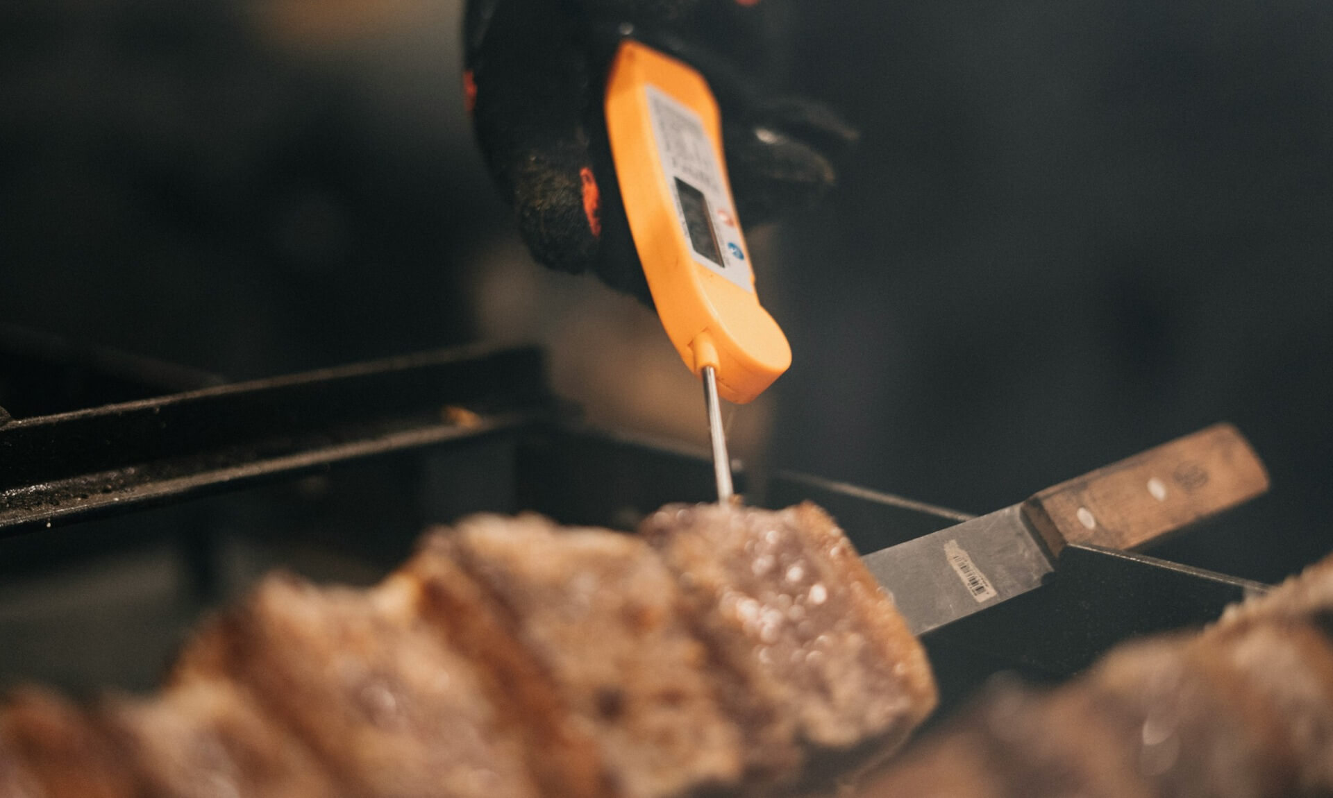A food thermometer probe inserted into a piece of meat on a barbecue