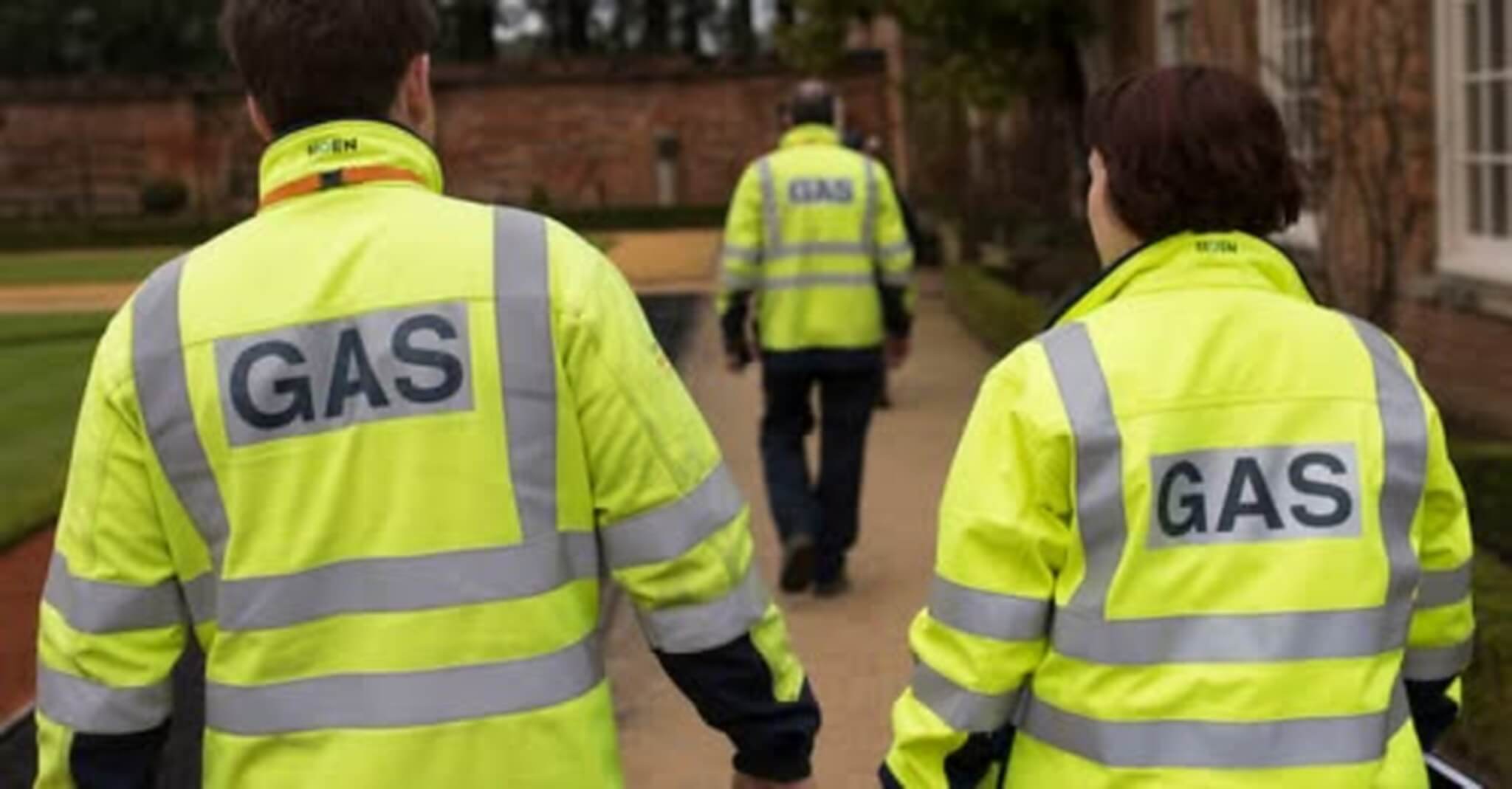 Gas engineers walking away from camera wearing hi-vis GAS jackets