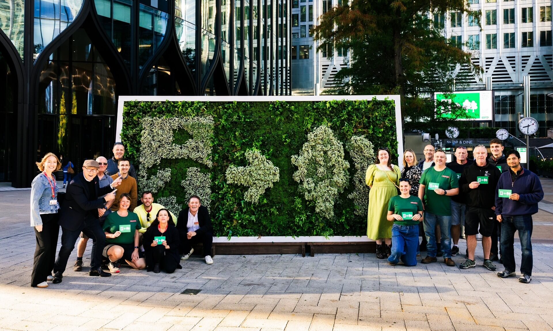 Volunteers and staff pose beside the living Emergency Exit sign at Canary Wharf