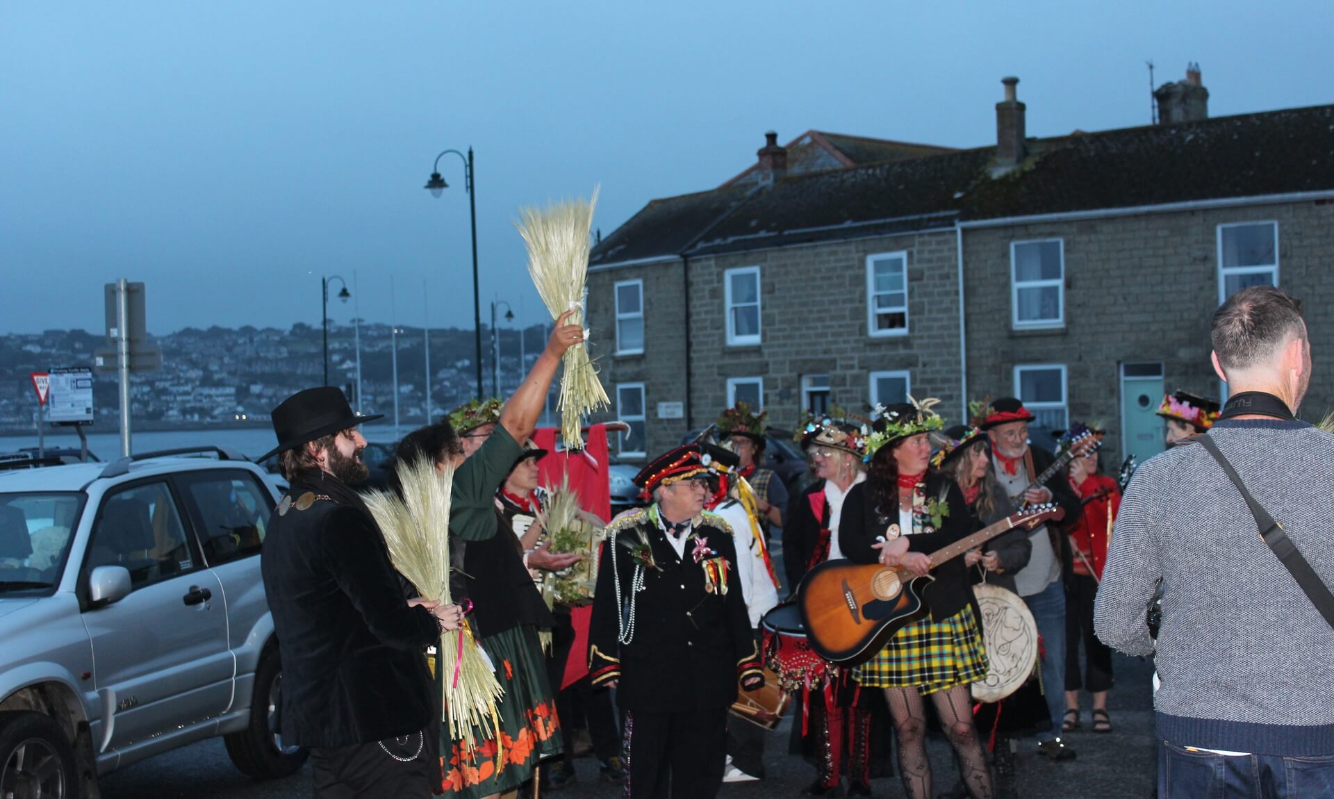 Guldize procession in Penzance, a bundle of corn held aloft by the harbour at dusk