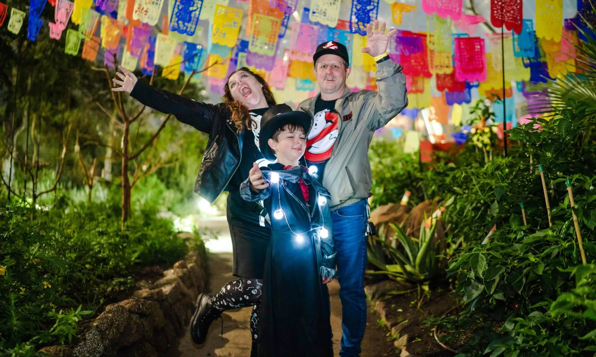 Family in Halloween costumes celebrating under colourful bunting at Eden Project Halloweden