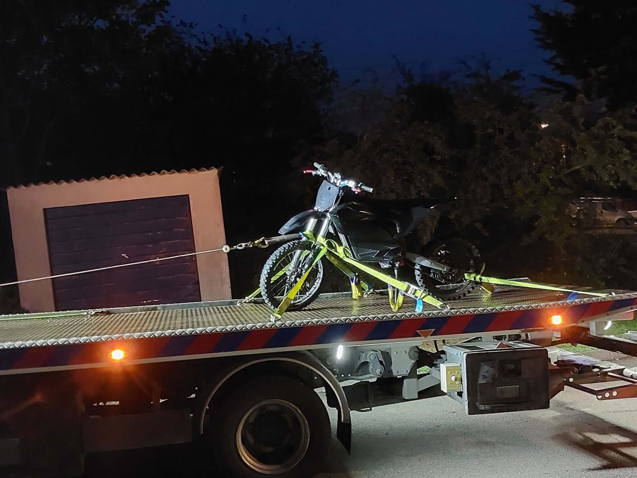 Surron style electric bike strapped to a recovery truck in Truro