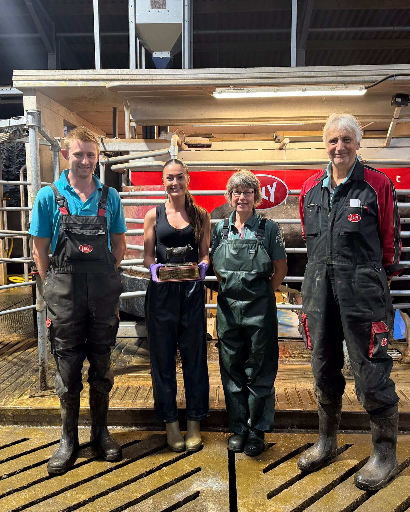 Holly holds her West Country Dairy Award trophy alongside three colleagues at a dairy unit