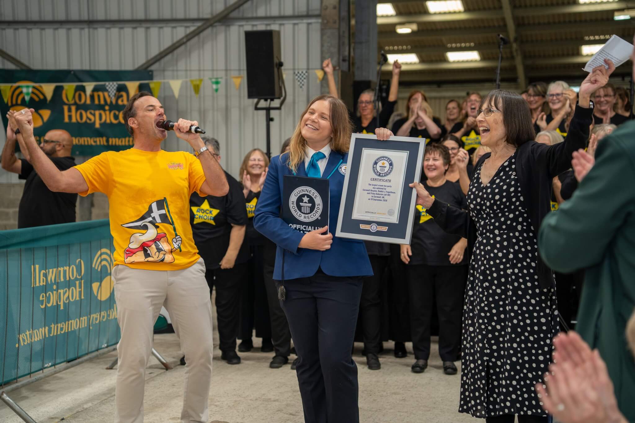 Johnny Cowling and a Guinness World Records adjudicator celebrate Cornwall Hospice's record cream tea party