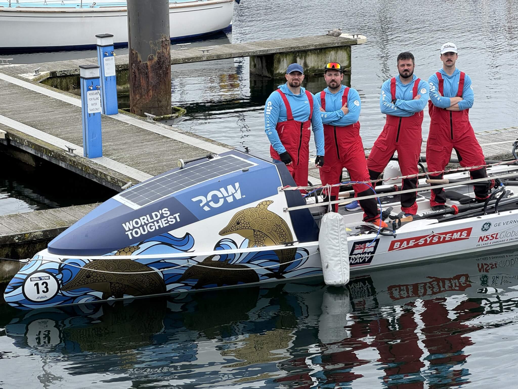 The HMS Oardacious crew standing on their ocean rowing boat