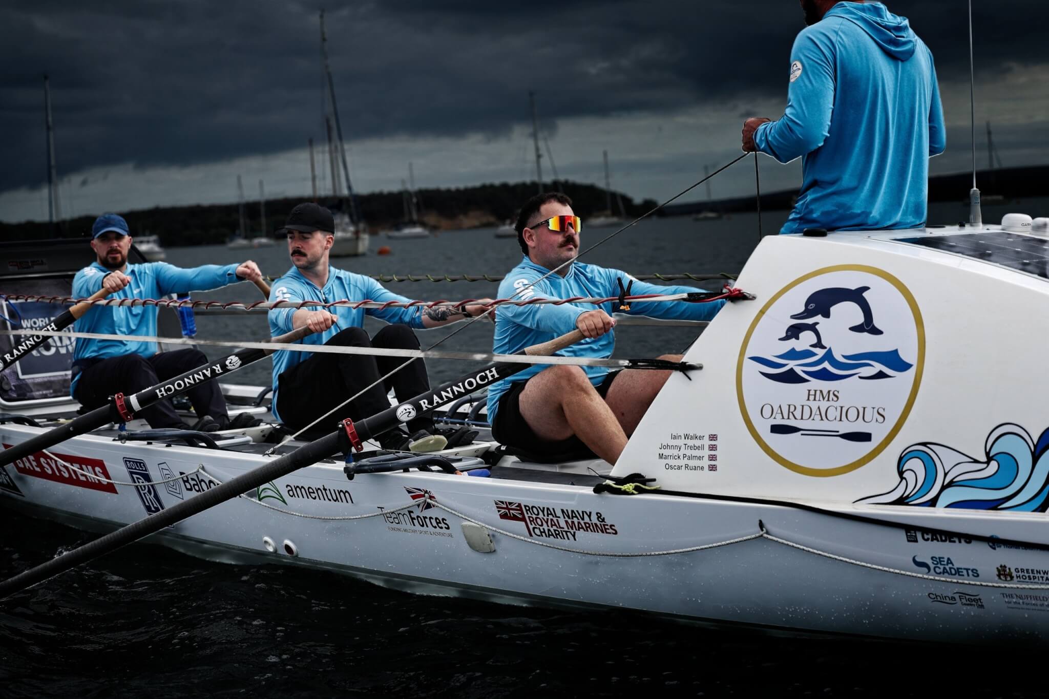 Crew rowing beside the HMS Oardacious logo