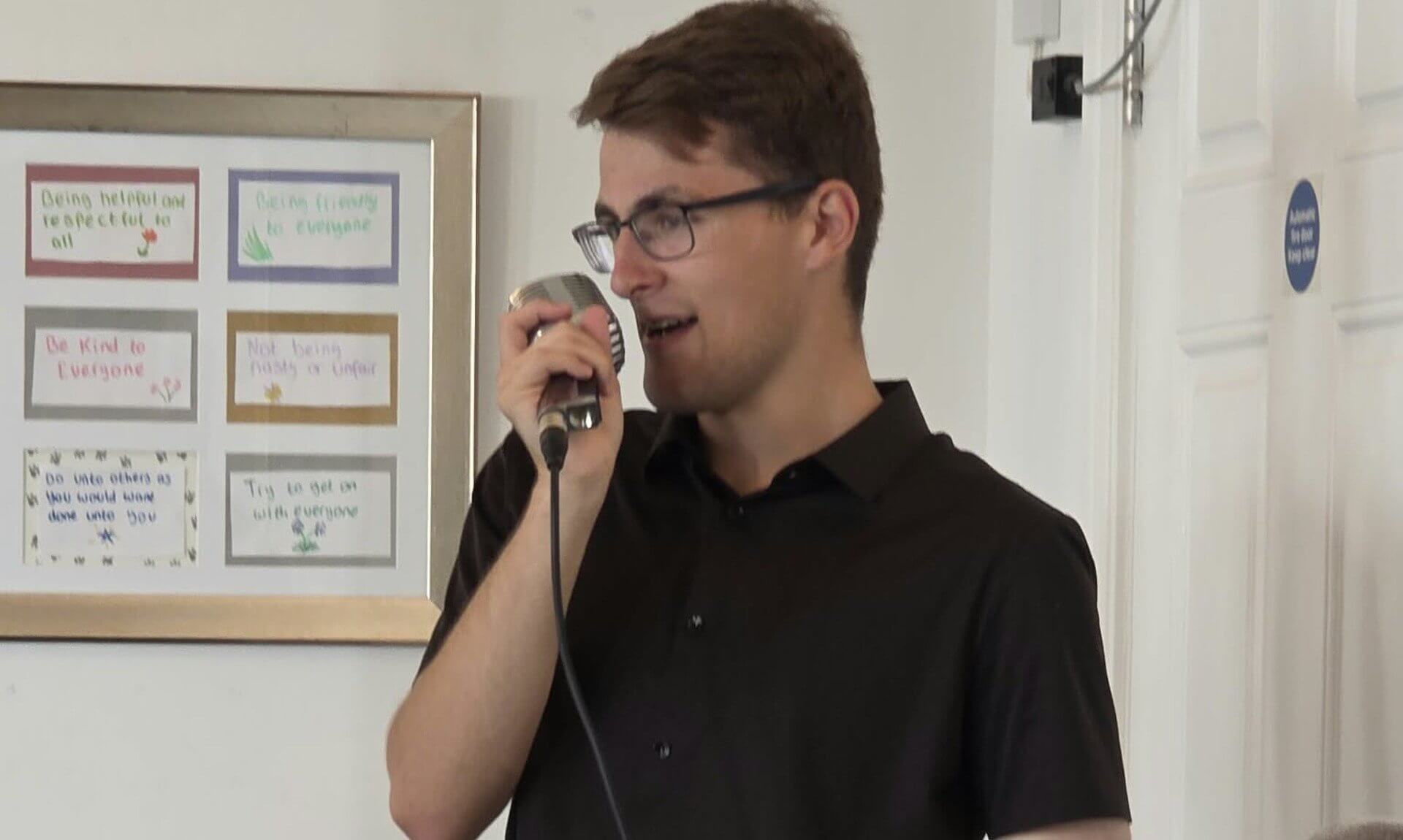 Jacob Reed singing into a vintage microphone at a care home