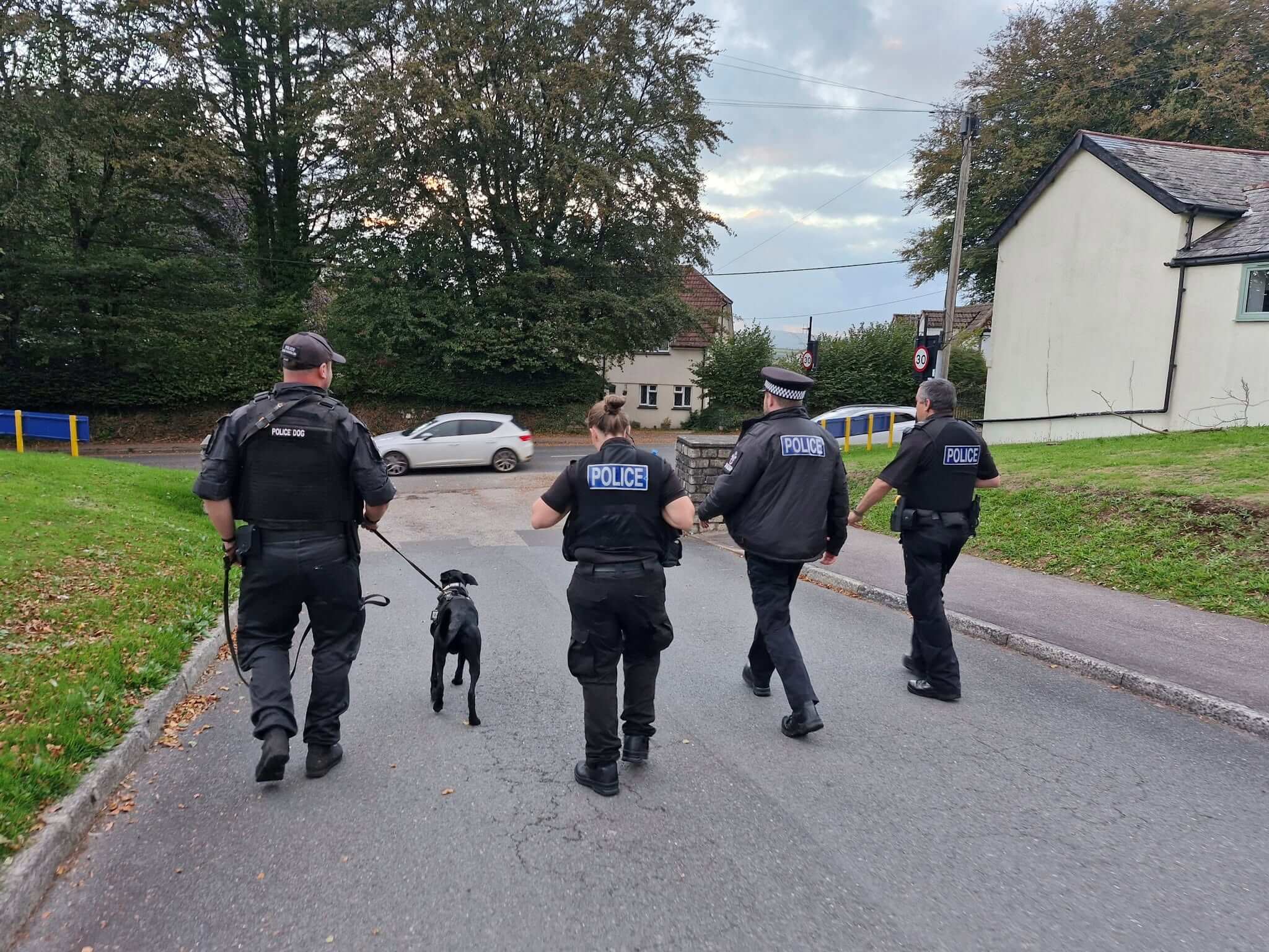 Four police officers walking with passive drugs dog Jasper